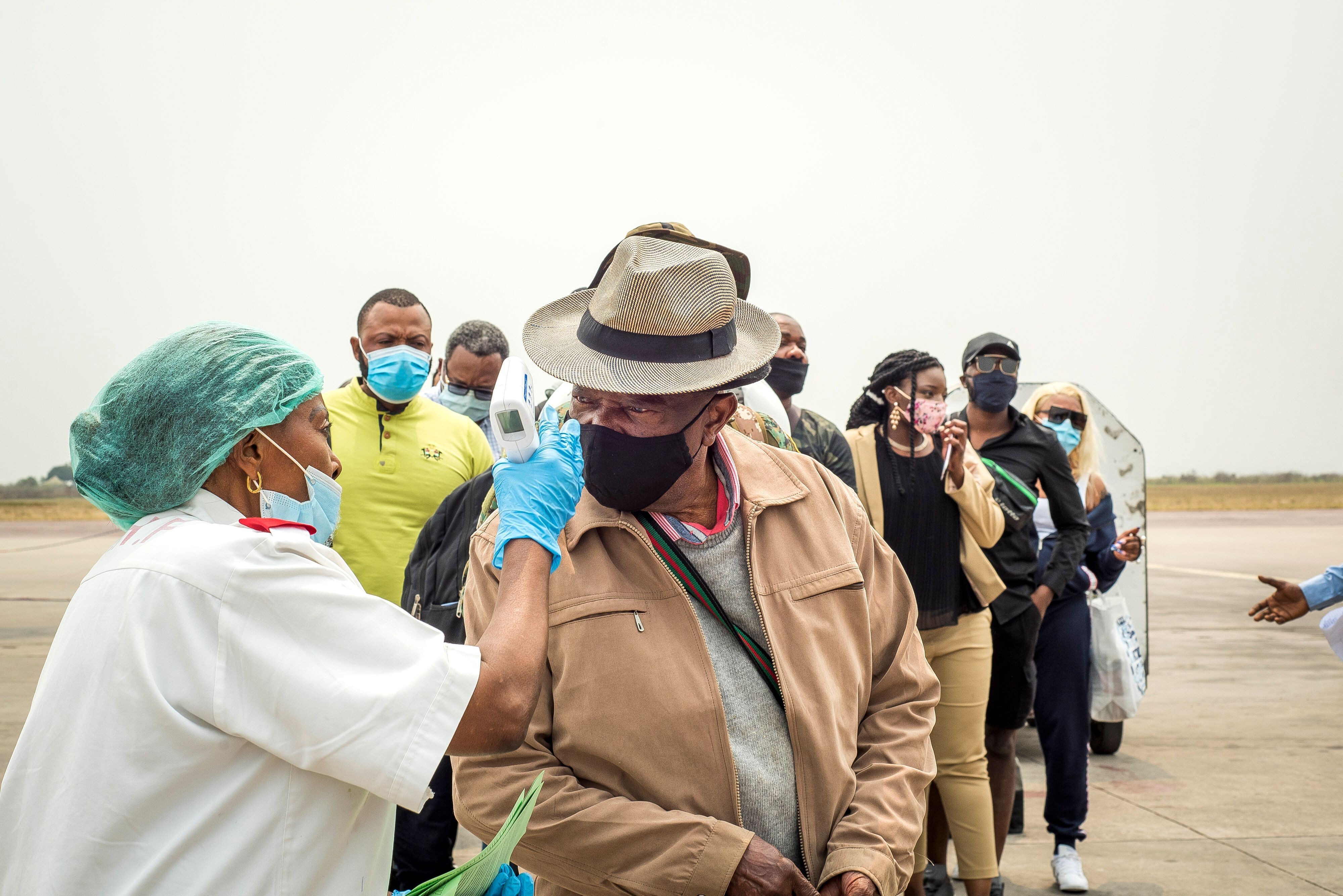 An airport worker takes the temperature of a passenger arriving at N'djili International Airport in Kinshasa on August 15. Congo’s multiple battles with Ebola have helped to prepare it for the fight against Covid-19. Photo: AFP