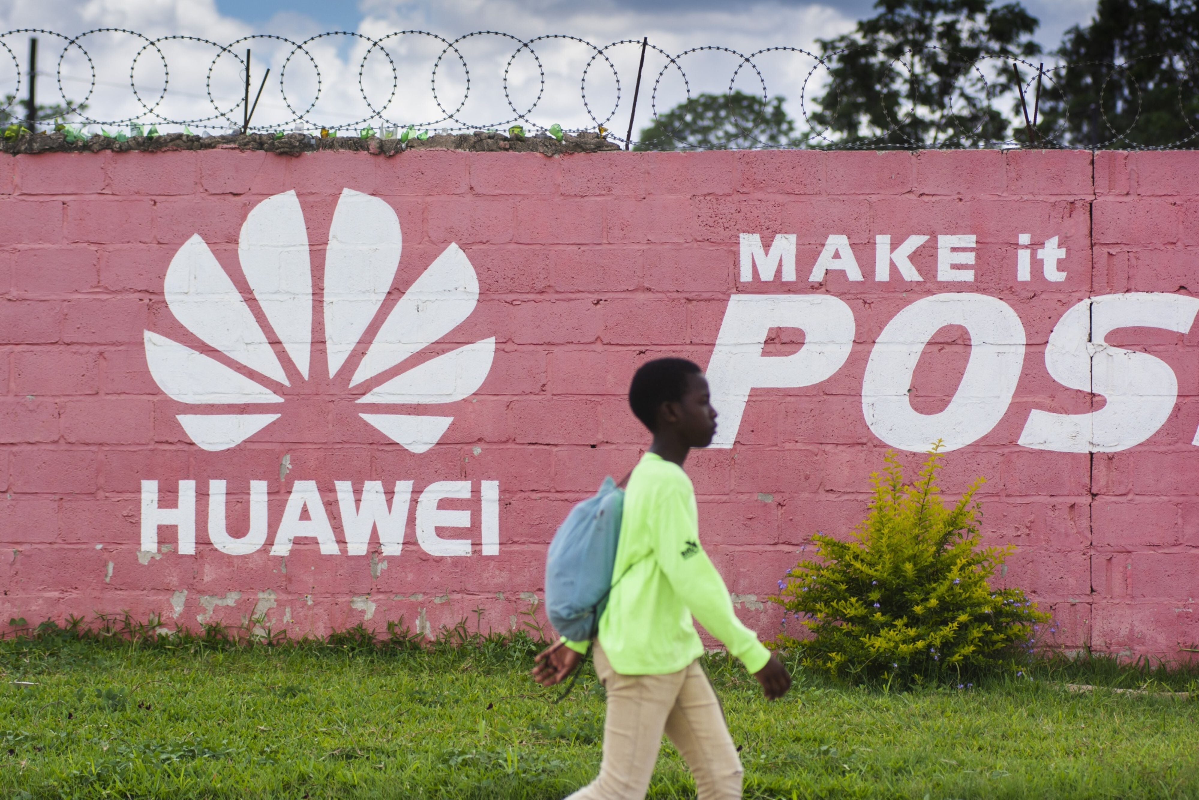 A pedestrian passes the Huawei logo painted on a wall in Lusaka, Zambia, on December 11, 2018. Many digital infrastructure projects in Zambia, like the more visible airport terminals and highways, are being built and financed by China. Photo: Bloomberg