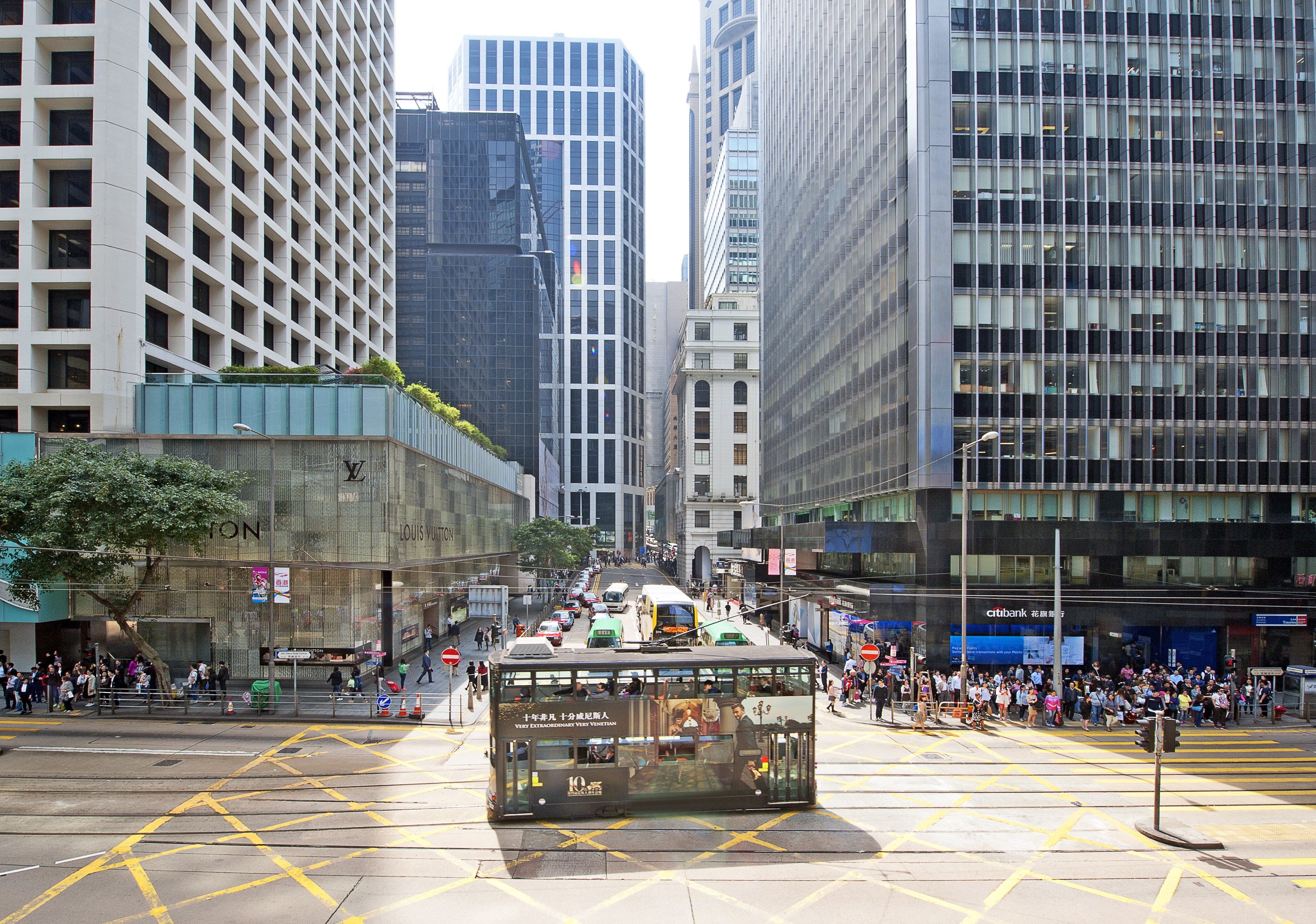 An iconic heritage double-decker tram passes a street junction in Central as it rides down the tramlines in the dedicated central reservation between high-rise skyscrapers in this street scene cityscape of the shopping and business district, Hong Kong Island. Photo: Getty Images