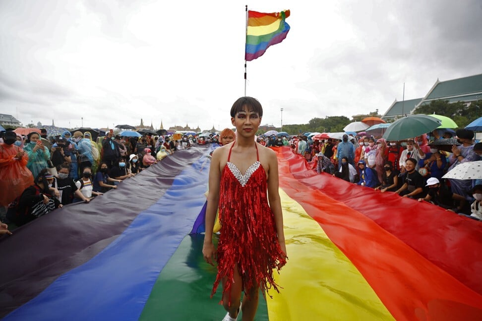 An LGBT protester walks on a rainbow flag laid out as a catwalk at Sanam Luang on September 19, 2020. Photo: EPA-EFE