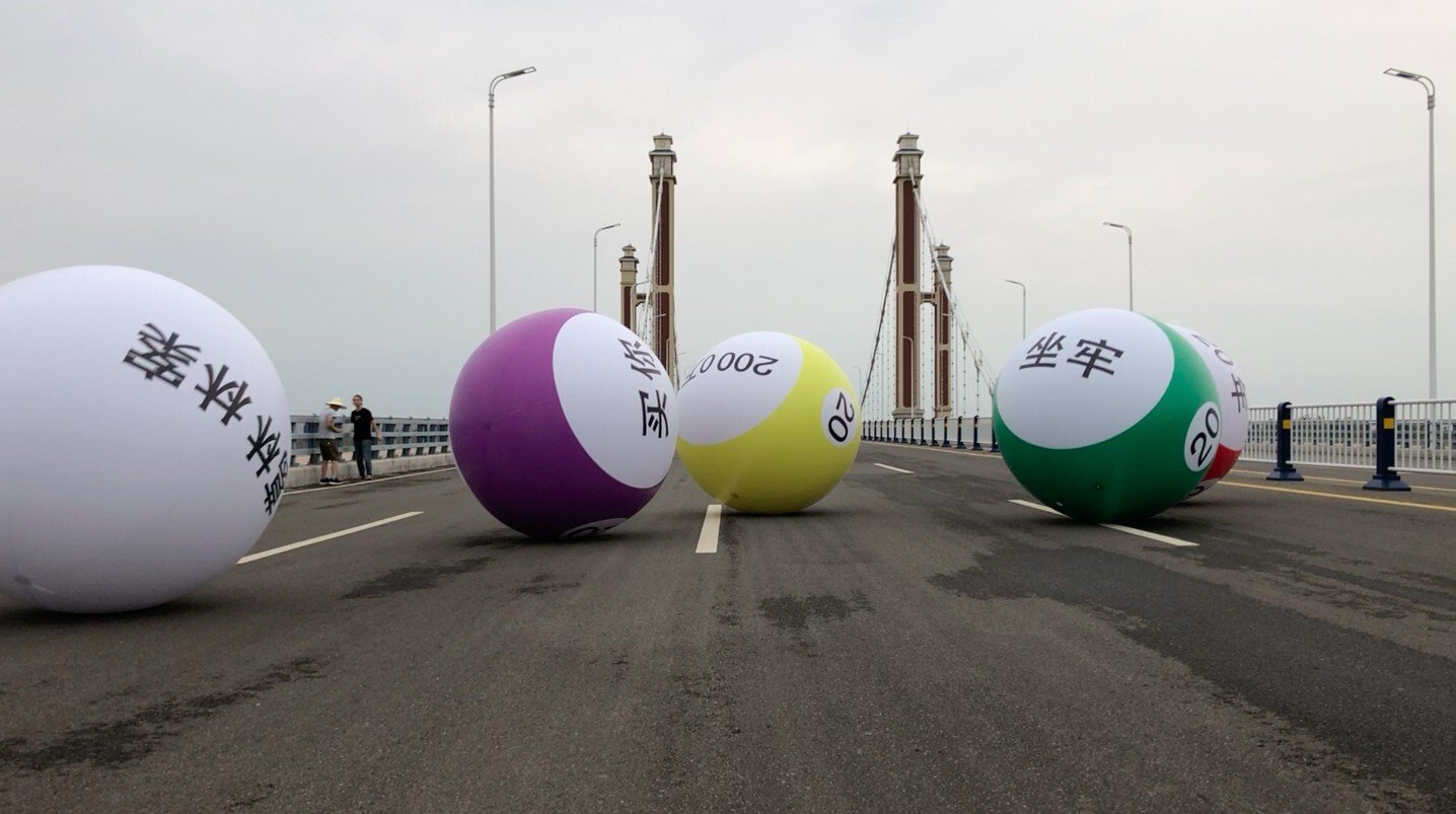 A screen shot from a video showing five giant inflatable balls rolling across a suspension bridge in Fuyang, eastern China, as part of an art project initiated by Tang Jie, who is fighting her husband's conviction and imprisonment for being a triad leader. Photo: The Starving Artist Project