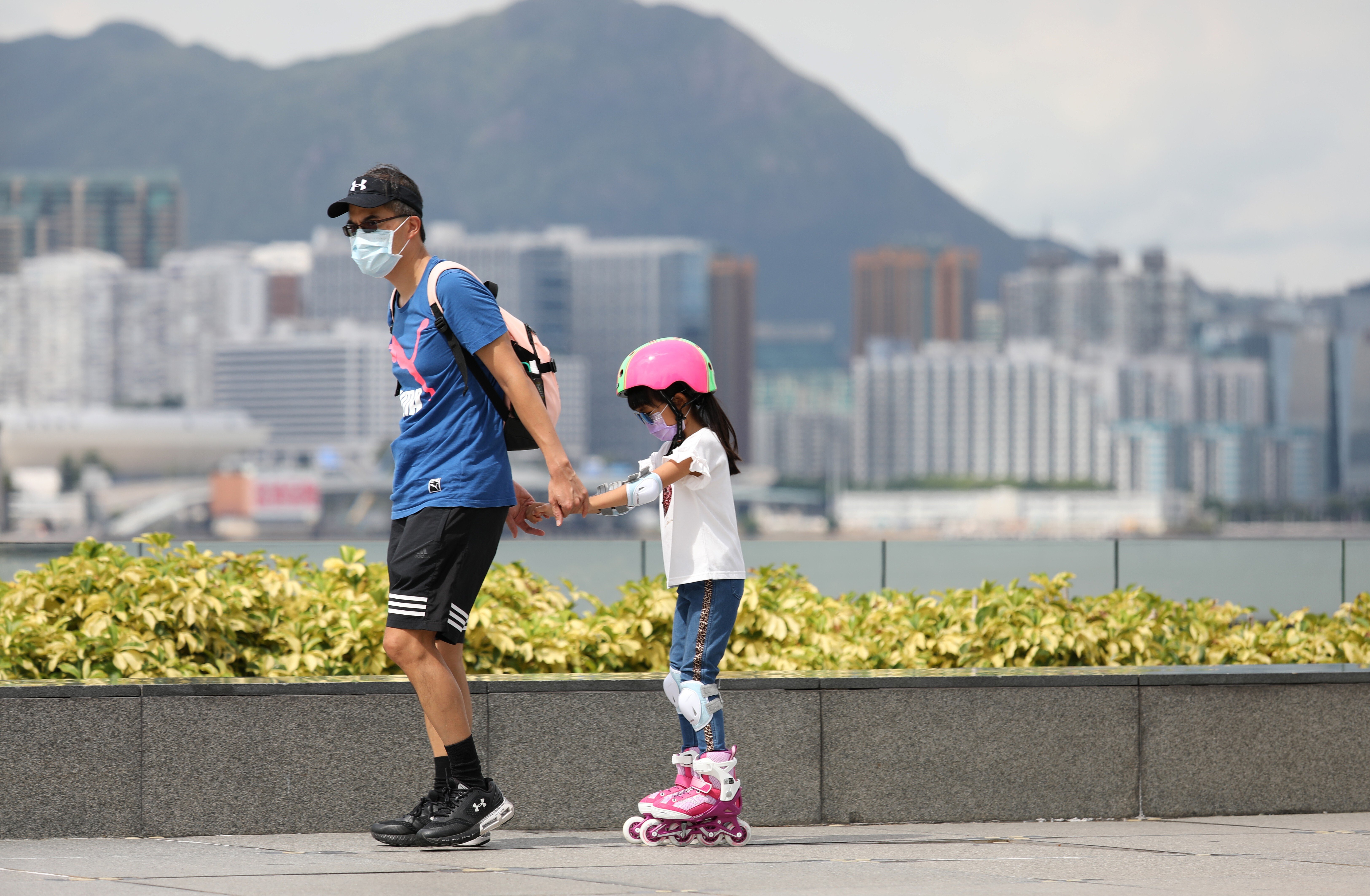 A man pulls along a girl on rollerblades at Tamar Park in Admiralty, Hong Kong, on August 10. Hong Kong has relaxed measures to contain the spread of Covid-19, but some restrictions remain. Photo: Nora Tam