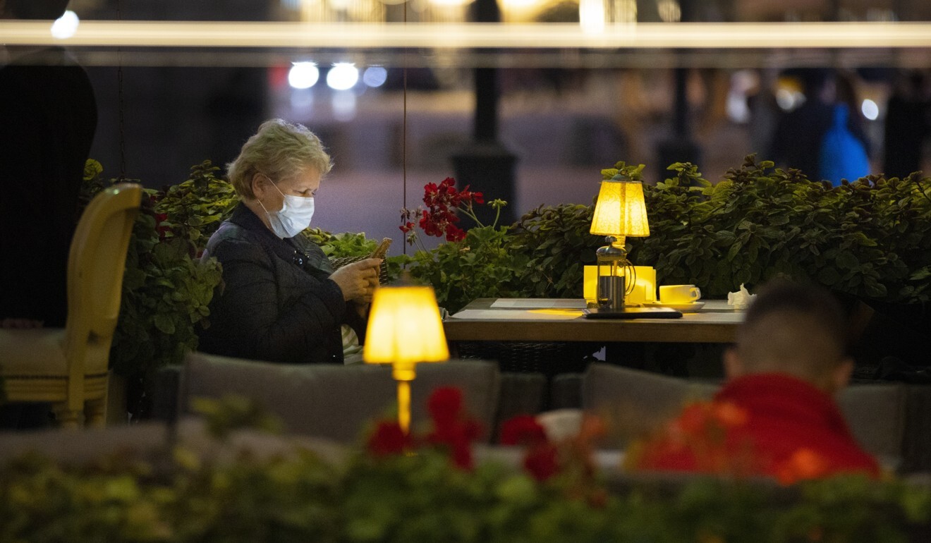 A woman wearing a face mask sits at a street-side cafe in Moscow on Friday. Photo: AP