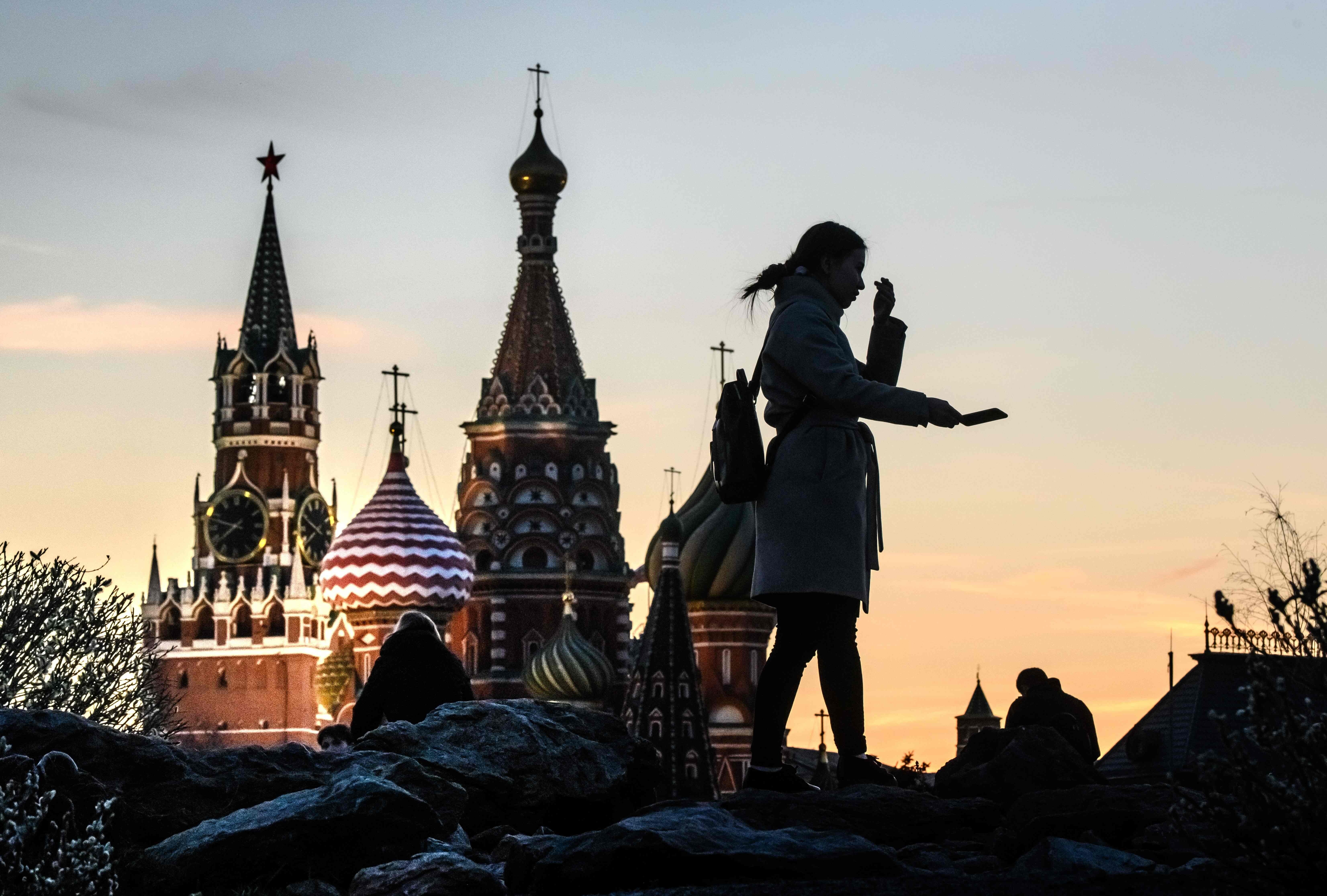 A woman takes a selfie in front of the Kremlin and St Basil’s Cathedral at sunset in Moscow on April 19, 2019. Declining oil prices and a global recession have raised fears about the sustainability of Russia’s economic model. Photo: AFP