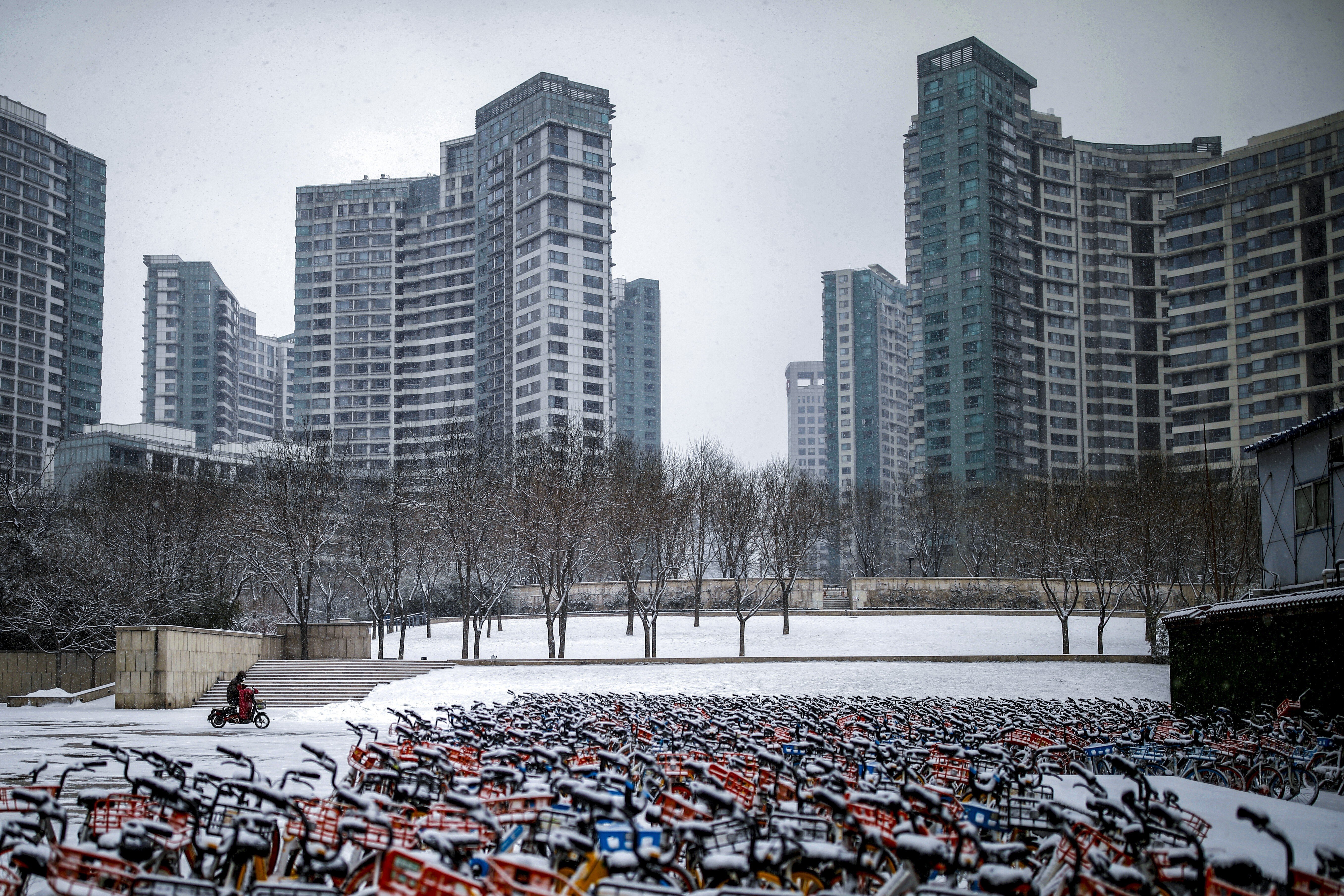 A person wearing a face mask rides an electric scooter with shared bikes parked nearby in Beijing on February 5. Picture: Reuters