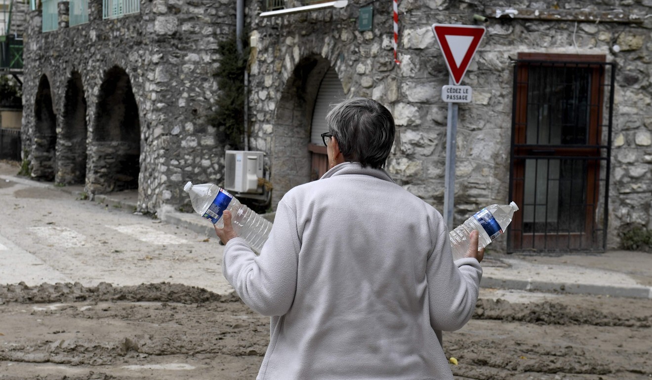 A woman carries bottles of water as she stands on a flooded street in Breil-sur-Roya, south-eastern France, on Sunday. Photo: AFP