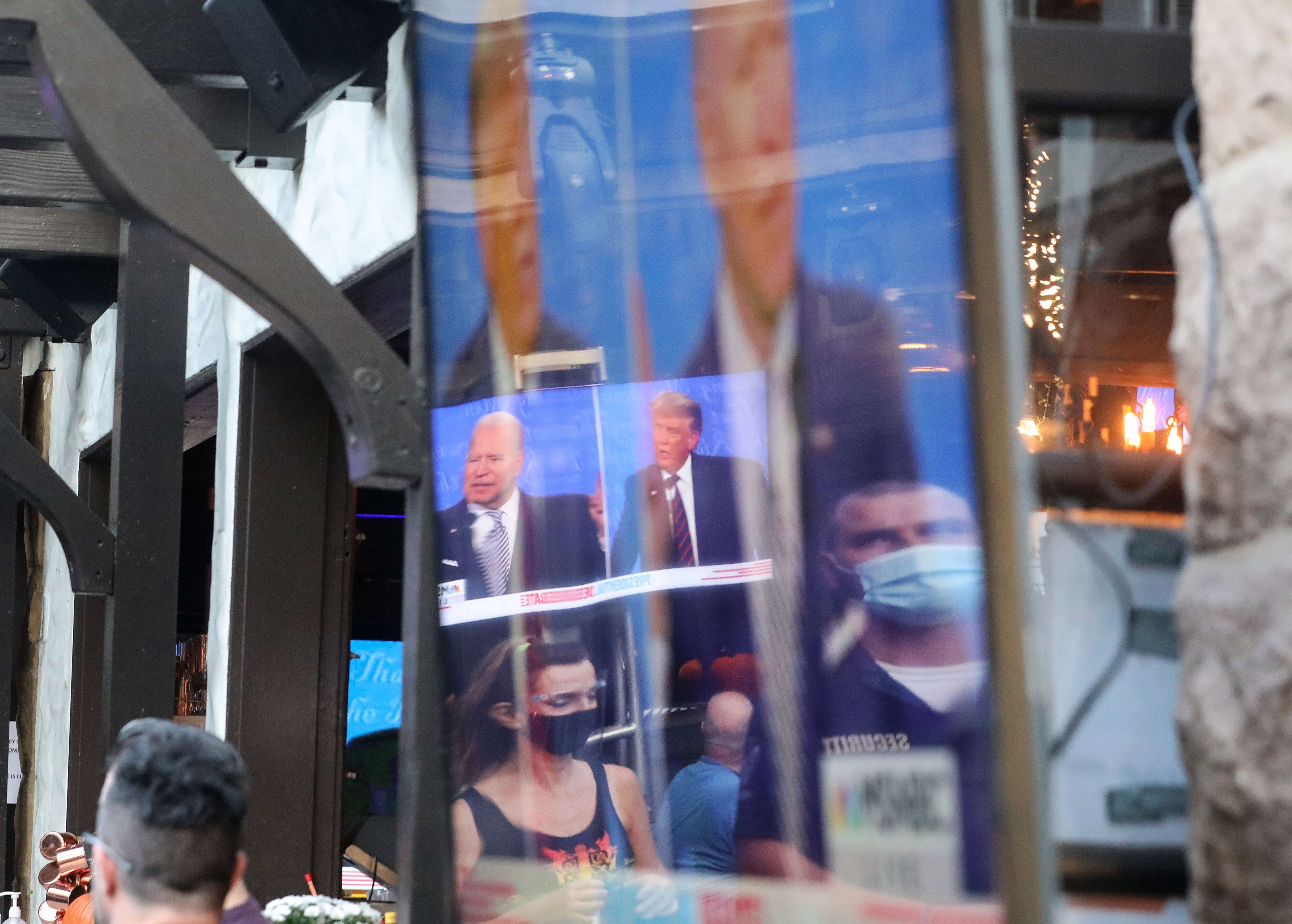People wearing face coverings are reflected in a television screen during the first debate between President Donald Trump and Democratic presidential nominee Joe Biden. Photo: AFP
