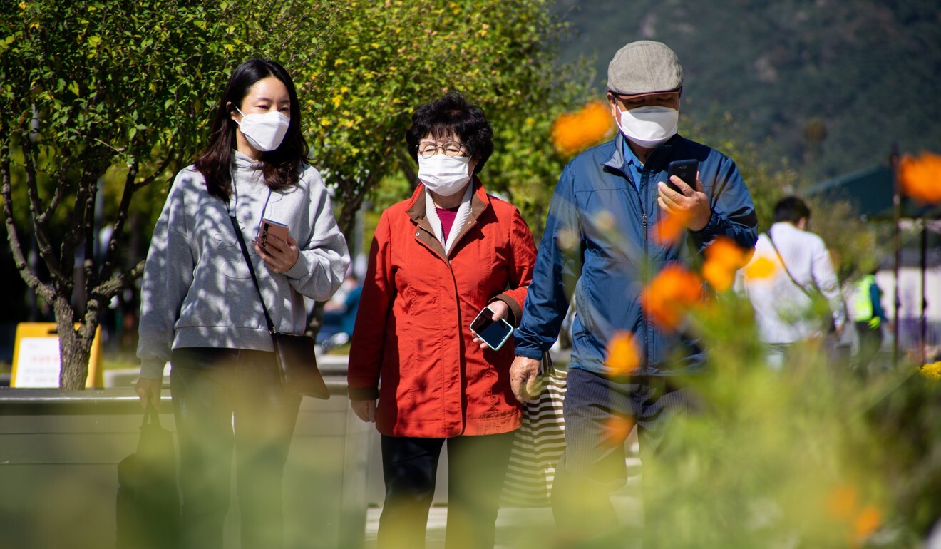 A family wearing face masks to guard against the coronavirus walk through Gwanghwamun Square in Seoul. Photo: EPA