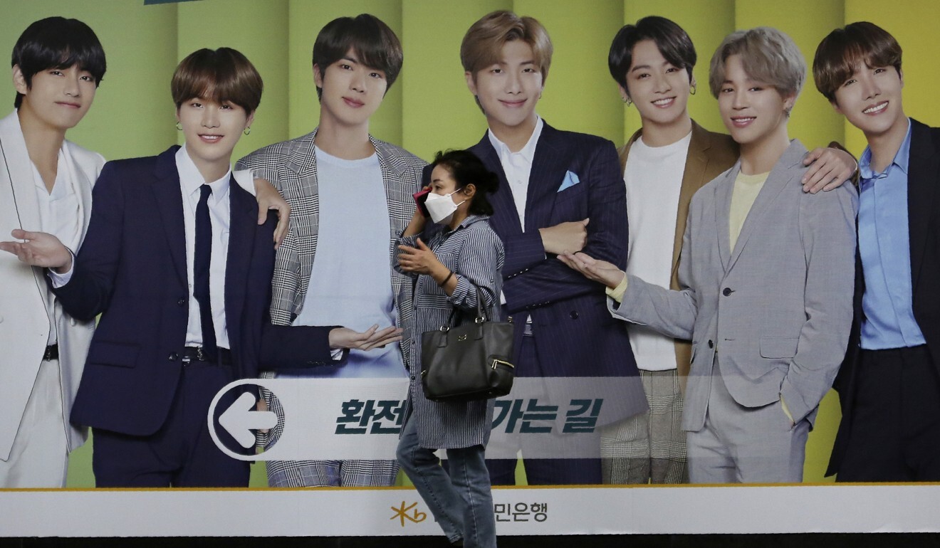 A woman wearing a face mask walks by a board showing members of K-pop group BTS in Seoul last month. Photo: AP
