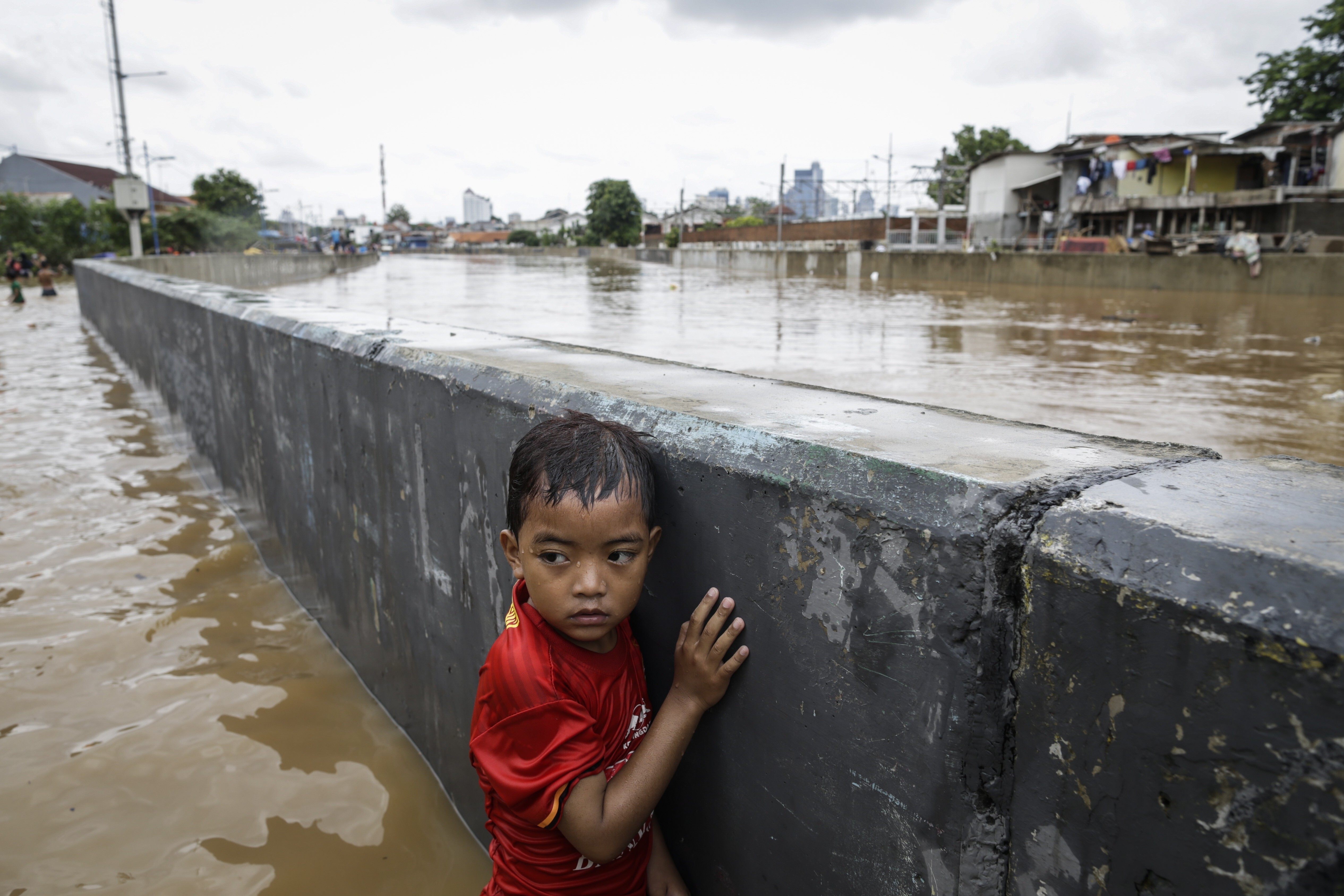 An Indonesian boy stands next to a wall at a flooded road in Jakarta, Indonesia, on January 2. Up to 95 per change of north Jakarta could be submerged by 2050 due to climate change, and climate-change-related insurance products are available in Indonesia. Photo: EPA-EFE