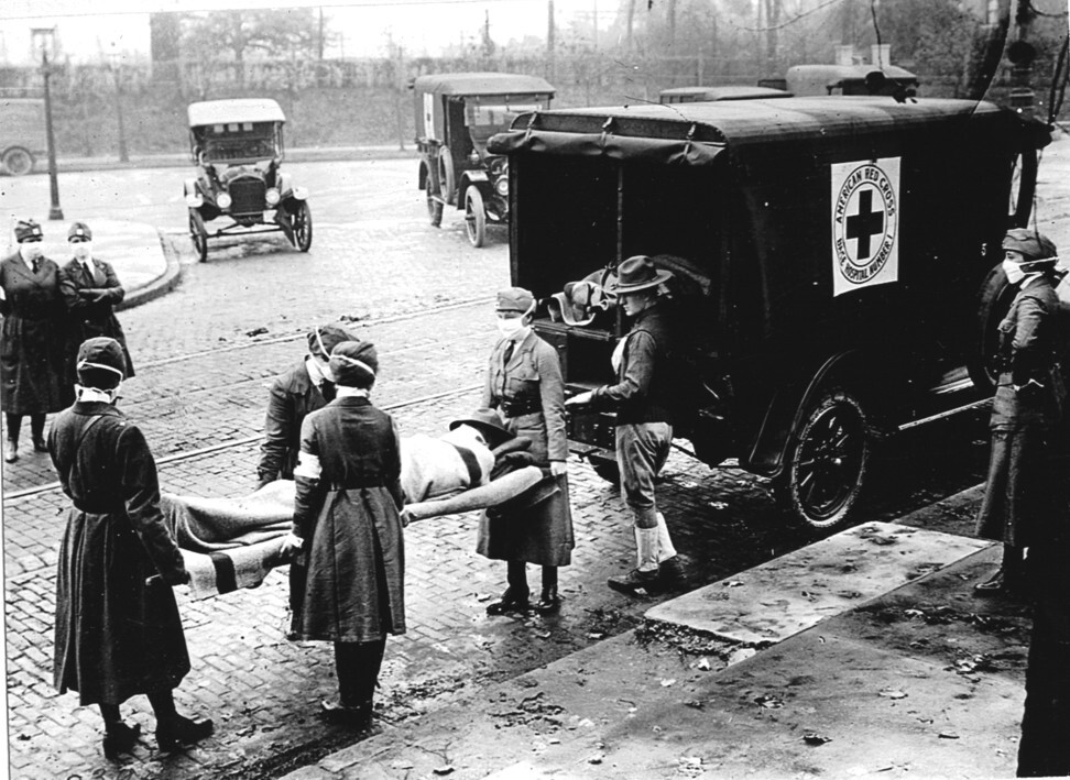 Members of the Red Cross, all wearing masks against the spread of the Spanish flu, put a patient on a stretcher into their ambulance, in Saint Louis, in the US state of Missouri, in October, 1918. Photo: Getty Images