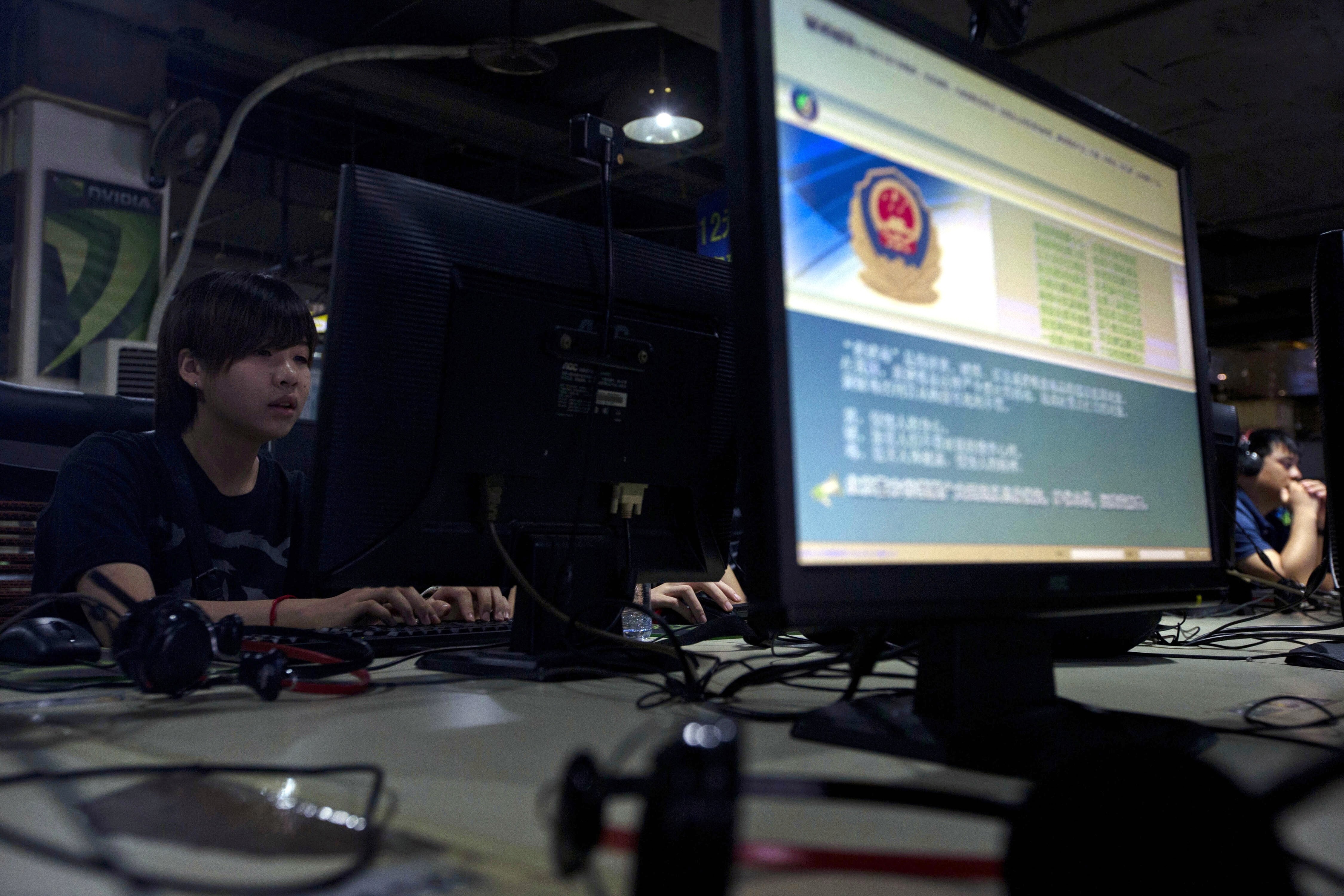 Computer users sit near a monitor display with a message from the Chinese police on the proper use of the internet at an internet cafe in Beijing. Photo: AP