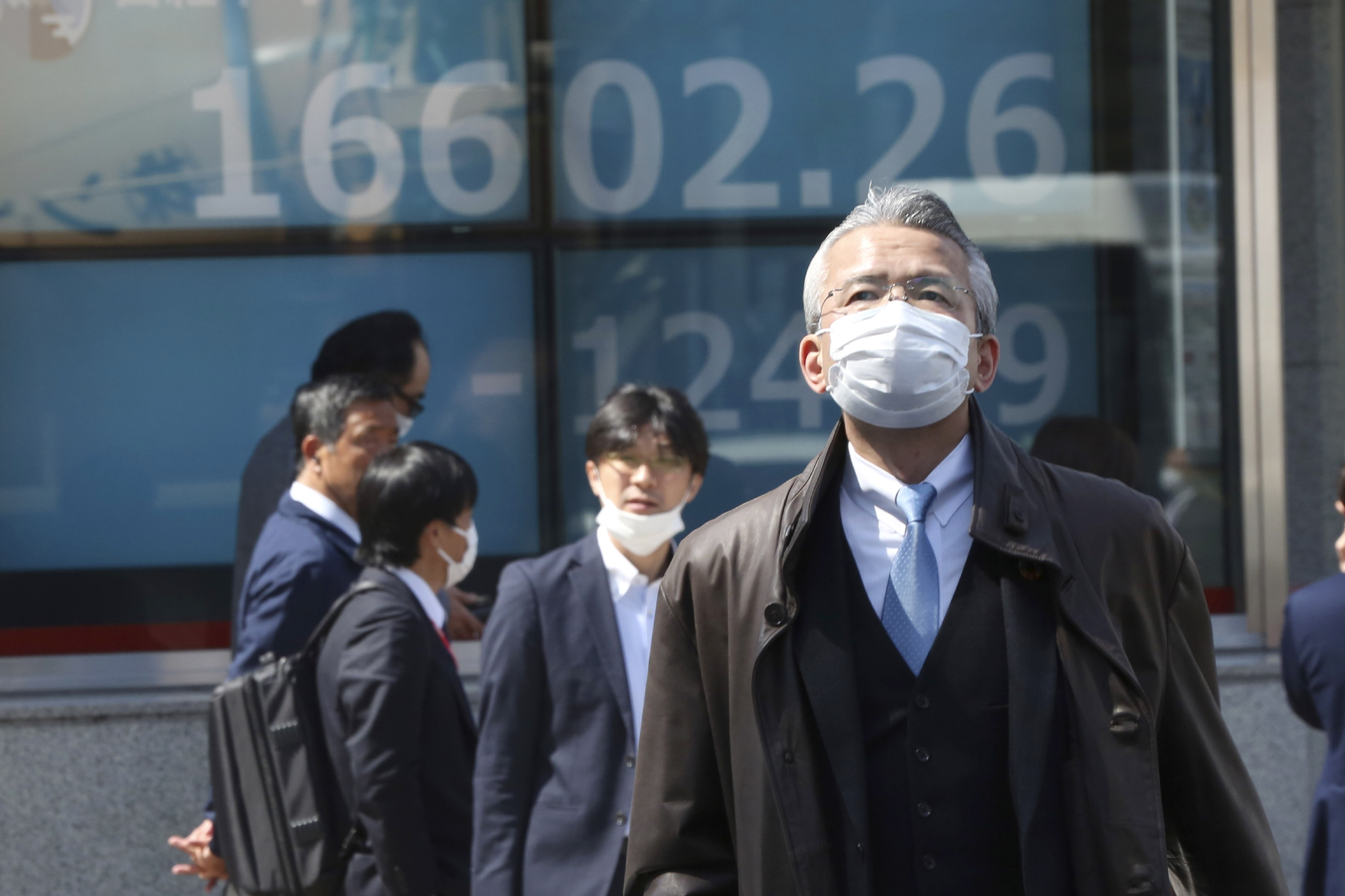 People walk by an electronic stock board of a securities firm in Tokyo, Japan in March 2020. Stocks in Asia-Pacific markets get a boost from progress in US stimulus talks. Photo: AP