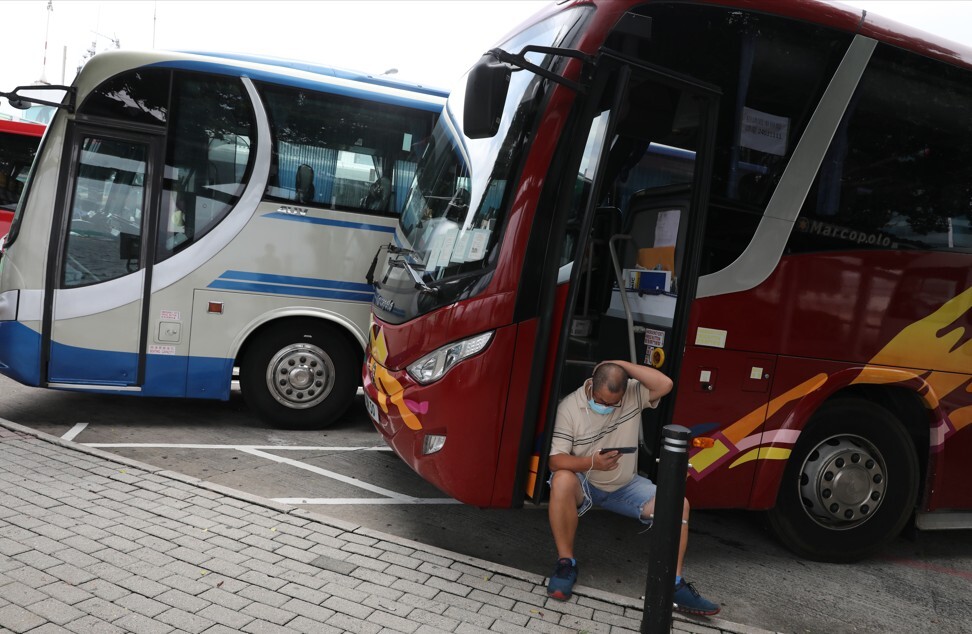A tour bus driver sits on the steps of his vehicle, outside the Hong Kong Convention and Exhibition Centre in Wan Chai. Photo: Nora Tam