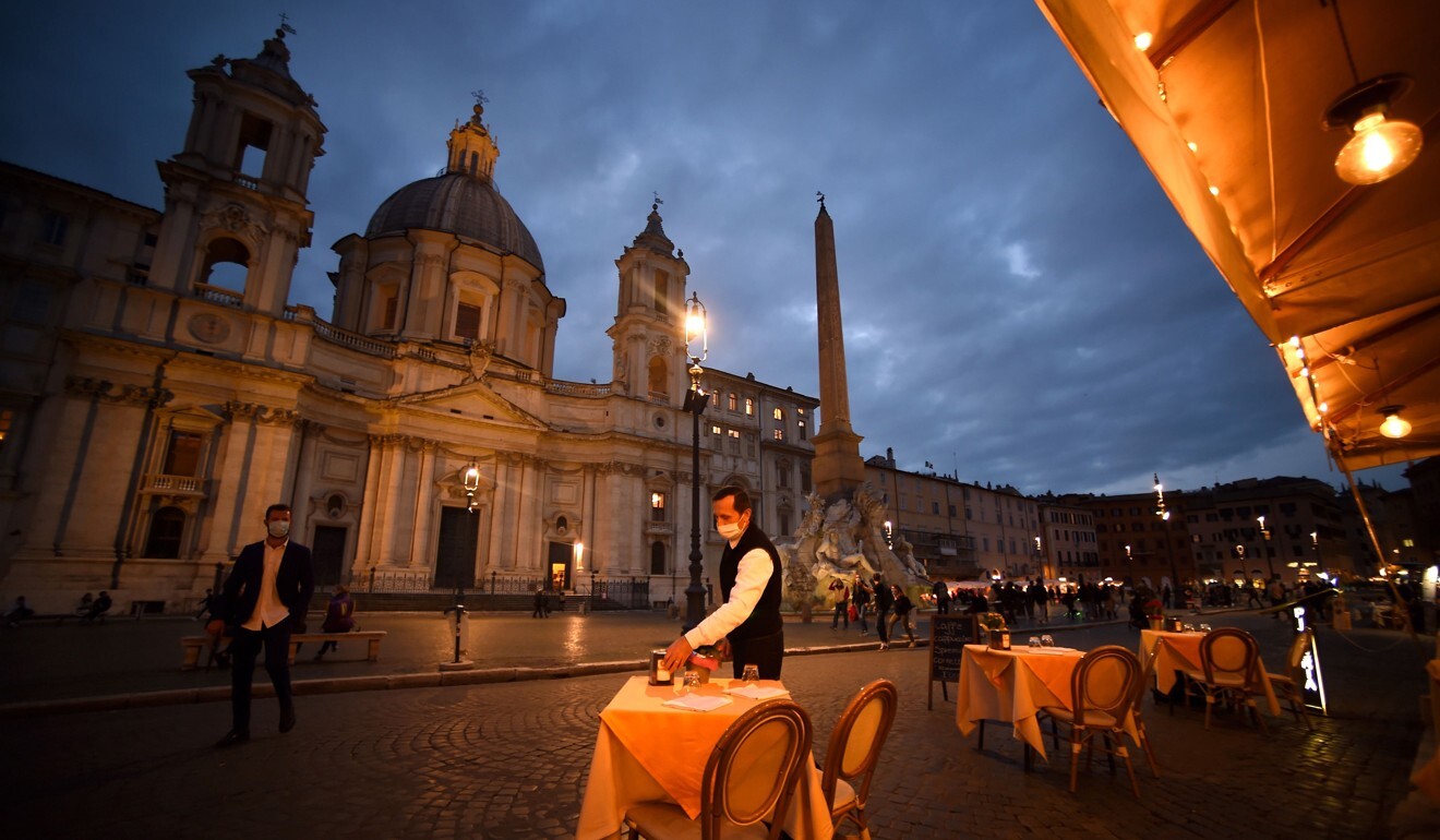 An employee cleans up a table on an empty terrace at Piazza Navona square in Rome on Thursday. Photo: TNS