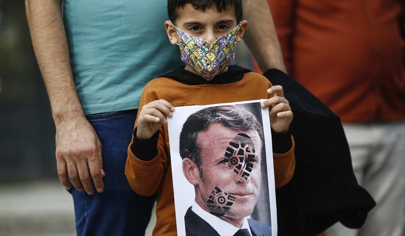 A child holds a photograph of France's President Emmanuel Macron, stamped with a shoe mark, during a protest against France in Istanbul on Sunday. Photo: AP