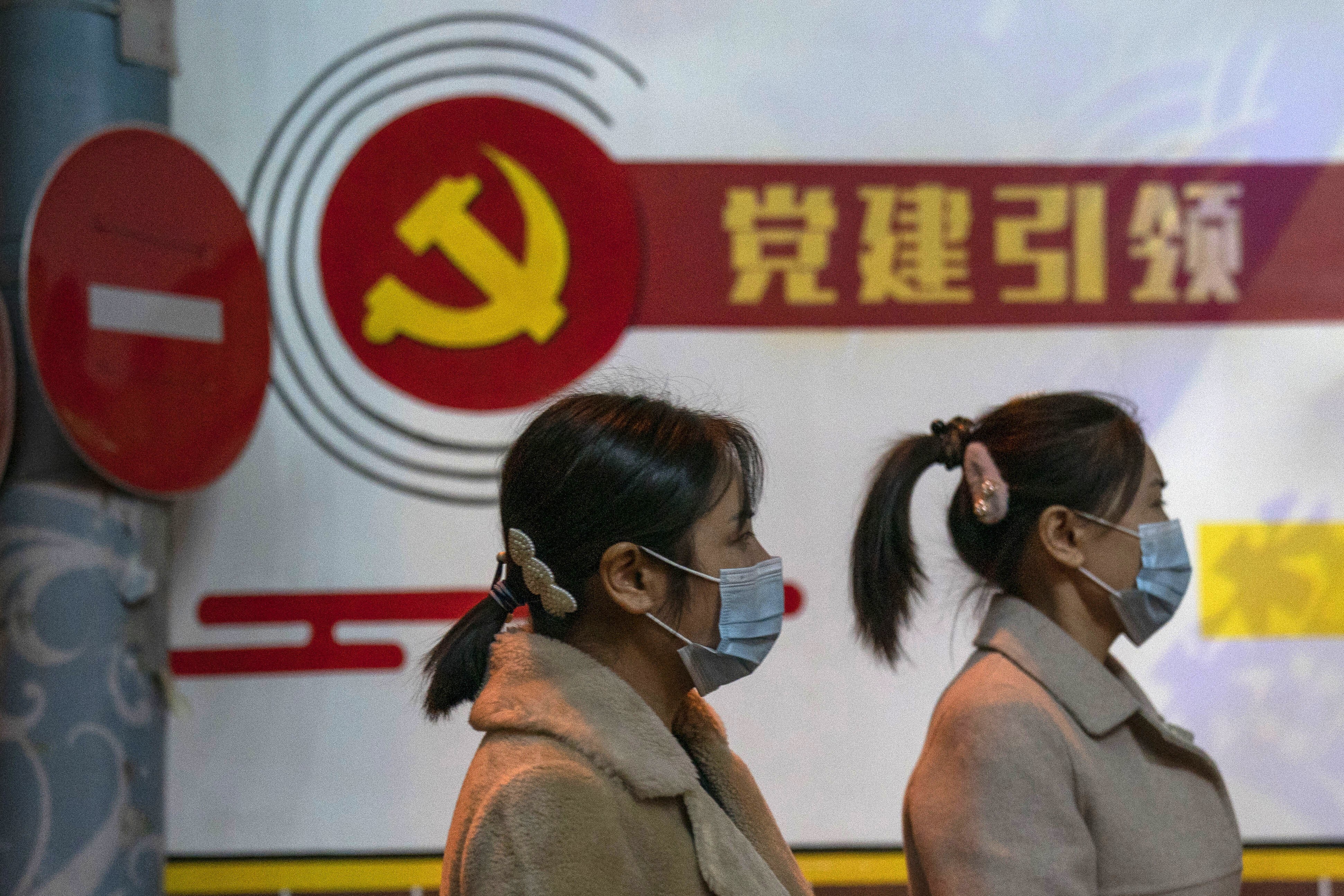 Pedestrians pass by the Communist Party logo and the slogan “Party building leadership” in Beijing on October 29. China says it will promote technological self-reliance in its latest five-year plan while still opening further to trade. Photo: AP