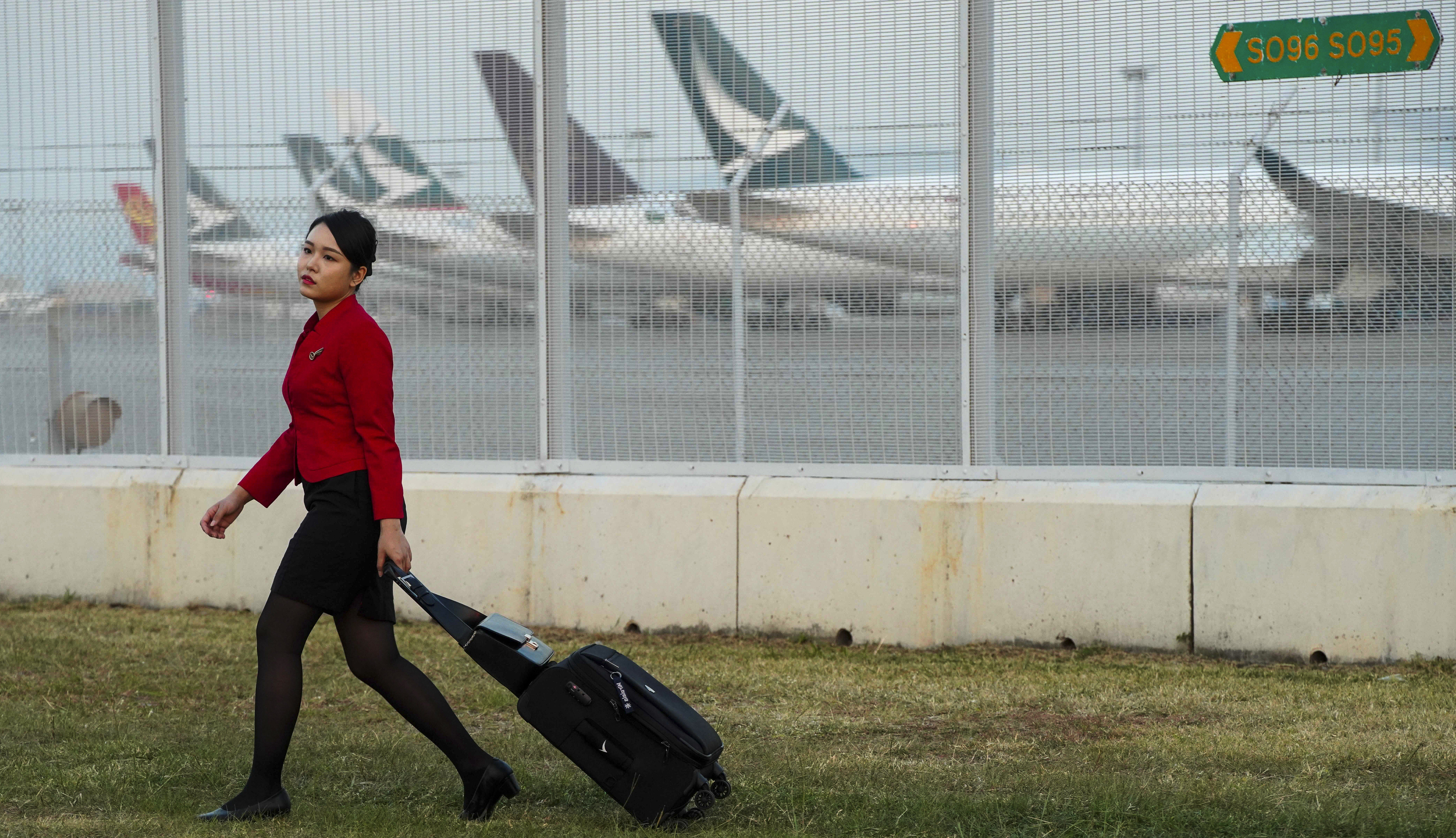 A Cathay Pacific flight attendant wheels her luggage past a parking bay for the company’s aircraft. Photo: Robert Ng