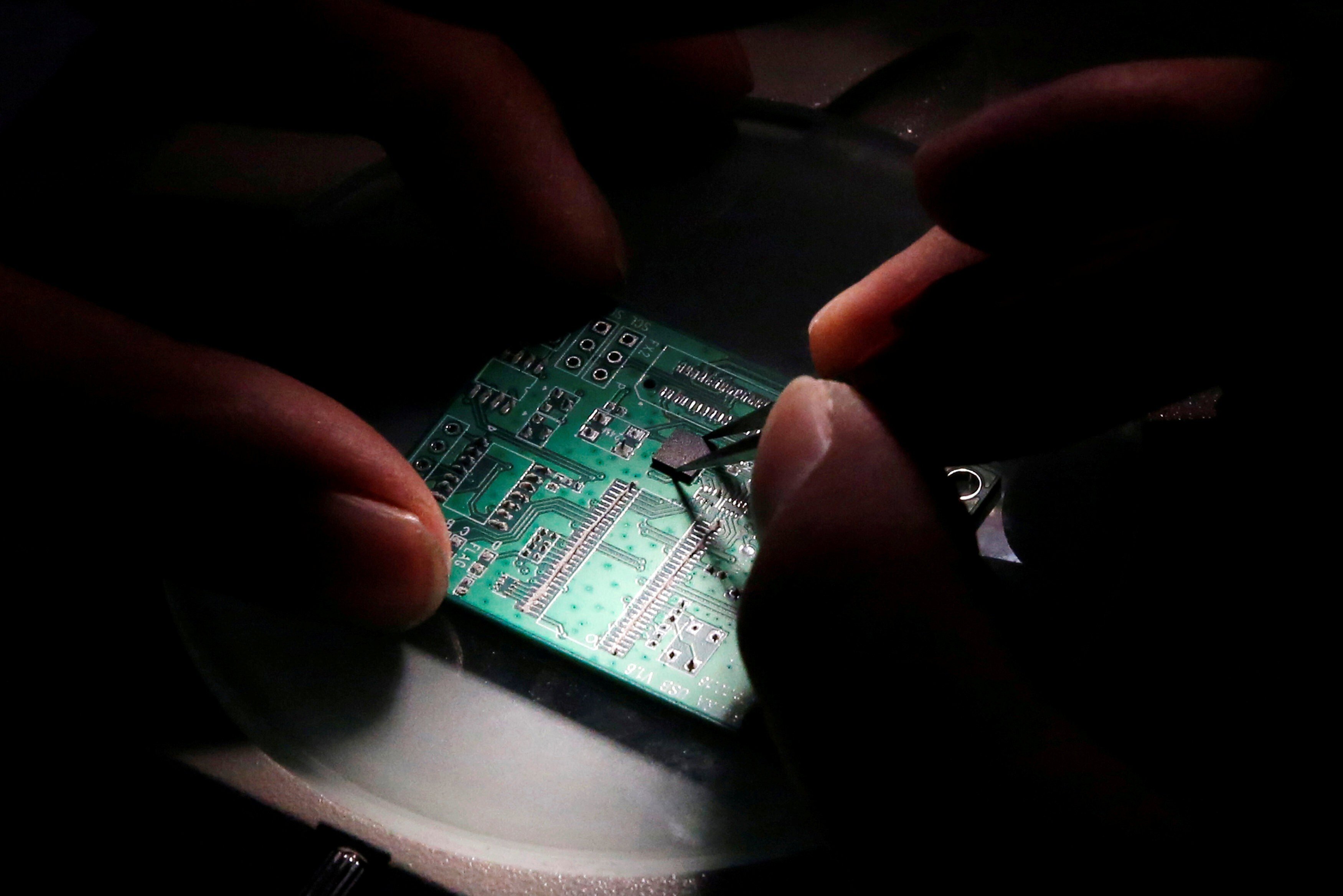 A researcher attaches a chip to a printed circuit board at Tsinghua Unigroup in Beijing. Photo: Reuters
