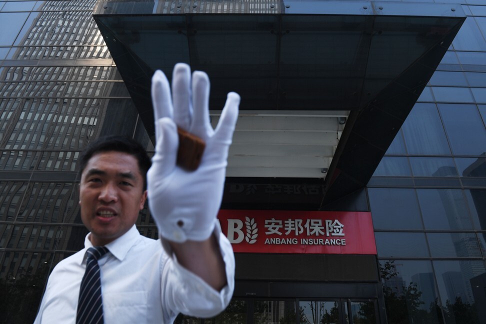 A security guard tries to prevent photos being taken outside the Anbang Insurance building in 2018. The company was seized a year earlier by Chinese authorities after its former chairman was accused of fraud. Photo: AFP