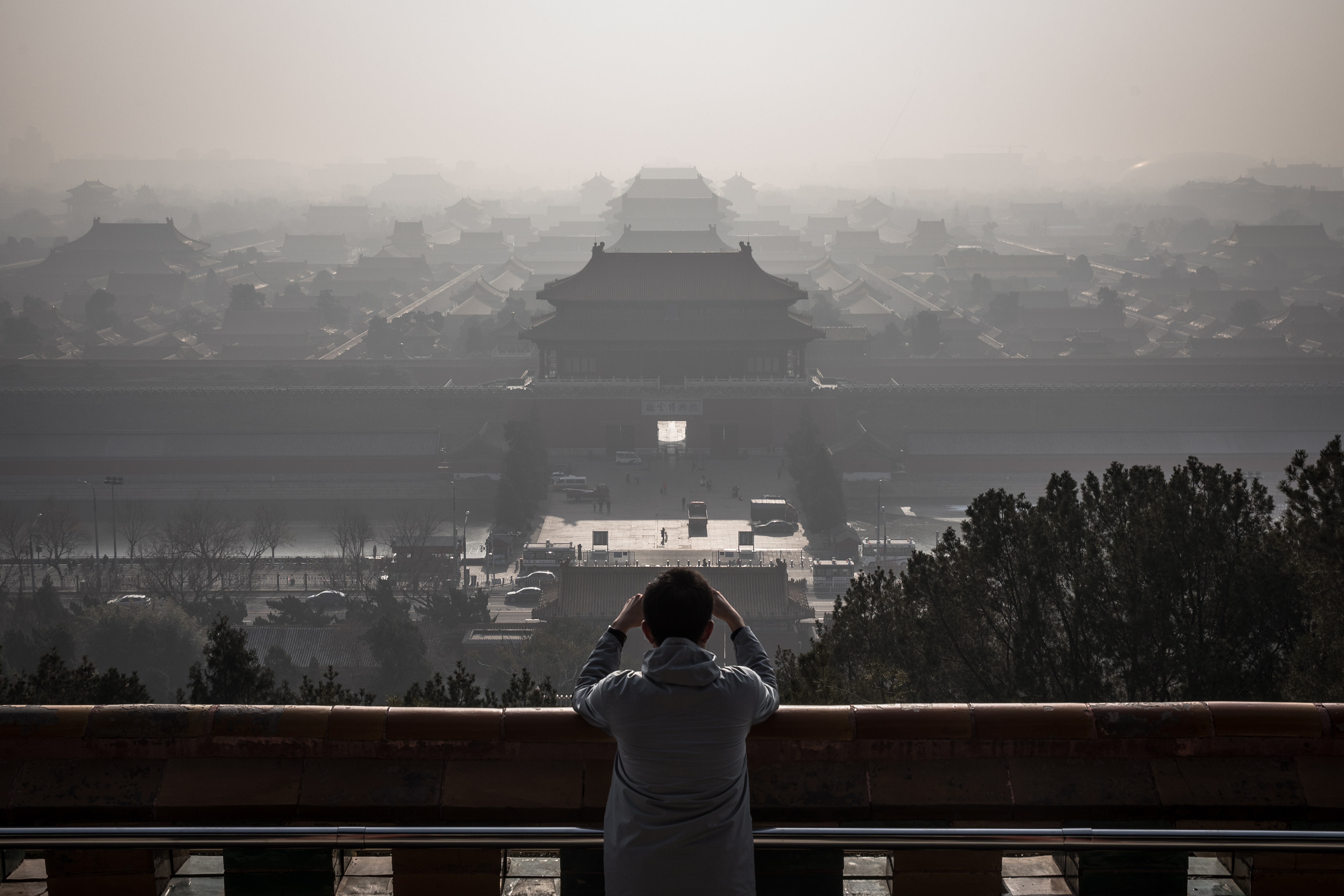 A man standing at a viewing area of Jingshan Park takes photos of the Forbidden City as a thick haze engulfs Beijing on December 9, 2019. China is hoping to establish itself as the new global leader in the fight against climate change, following the United States’ withdrawal from the Paris Agreement signed in 2015. Photo: EPA-EFE