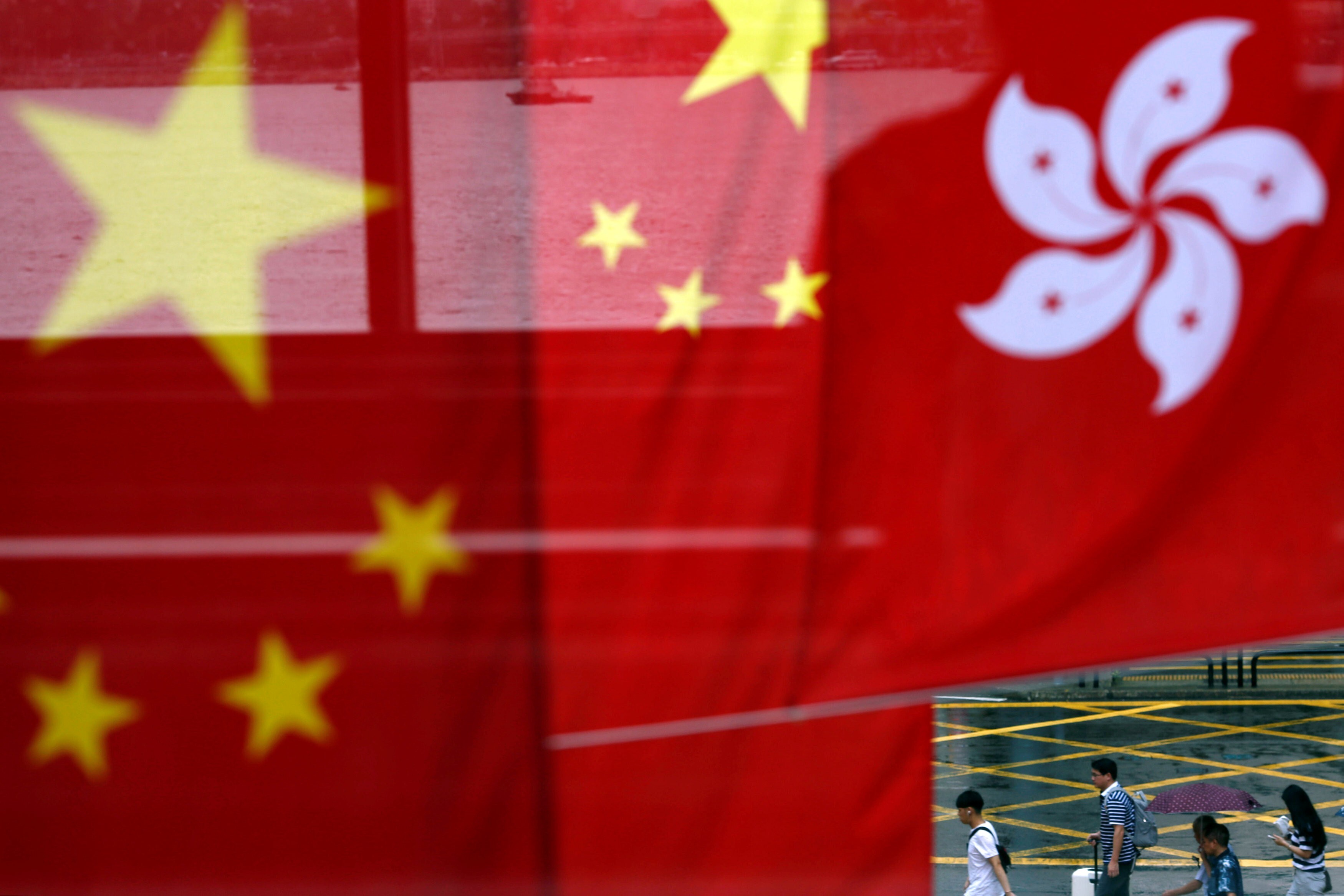 People walk past the Chinese and Hong Kong flags after celebrations commemorating the 20th anniversary of Hong Kong’s handover to Chinese sovereignty from British rule, on July 2, 2017. Photo: Reuters