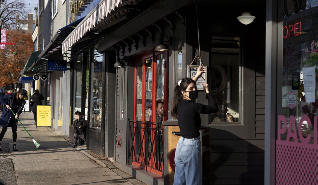 A worker wearing a protective mask opens an awning outside a restaurant in the West 4th shopping district in Vancouver, British Columbia, Canada, on November 21. Photo: Bloomberg