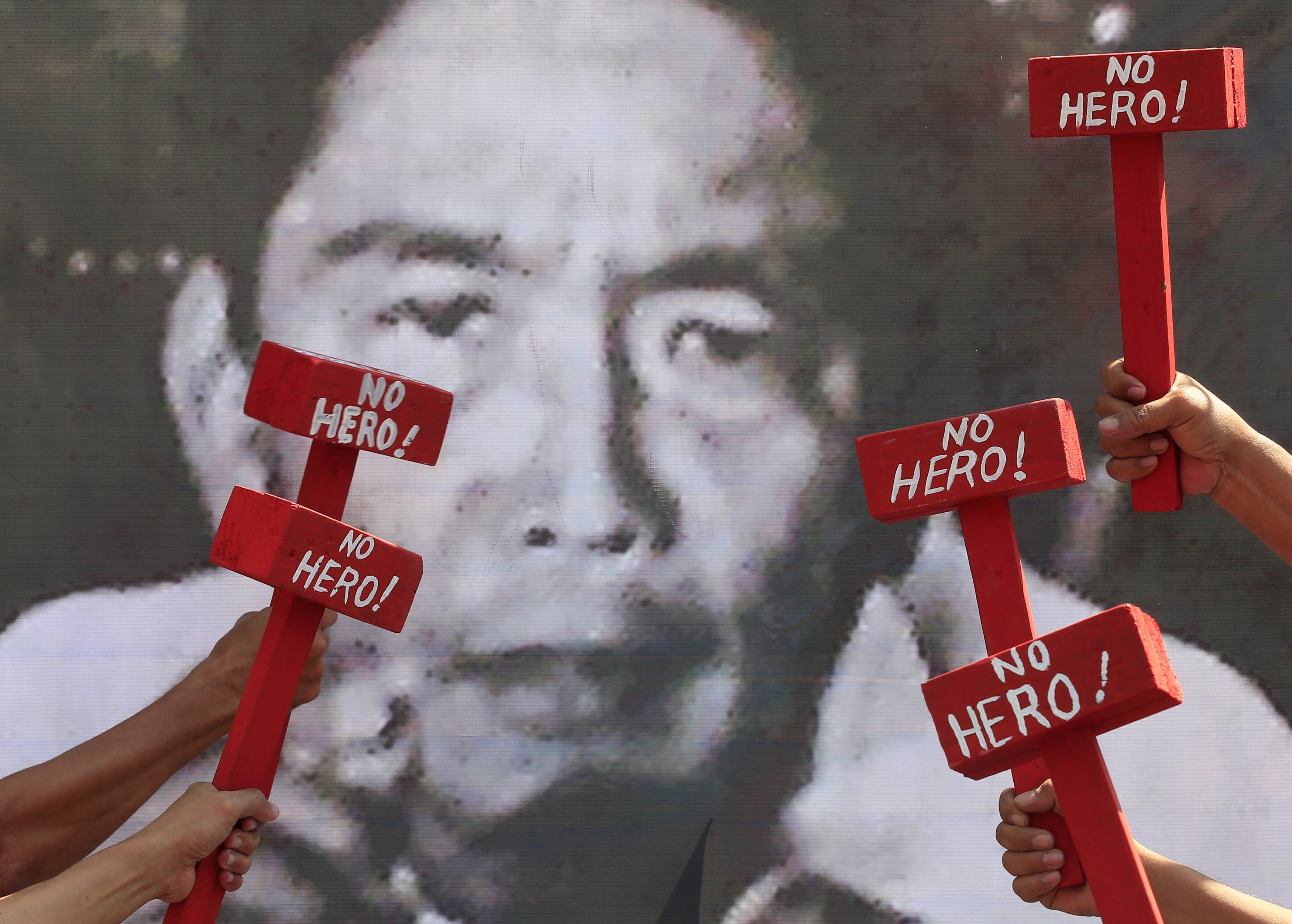 Protesters hold mock hammers with the words “No Hero” in front of a portrait of the late president Ferdinand Marcos as they denounce his burial at the Heroes' Cemetery in Manila in November 2016. Photo: Reuters