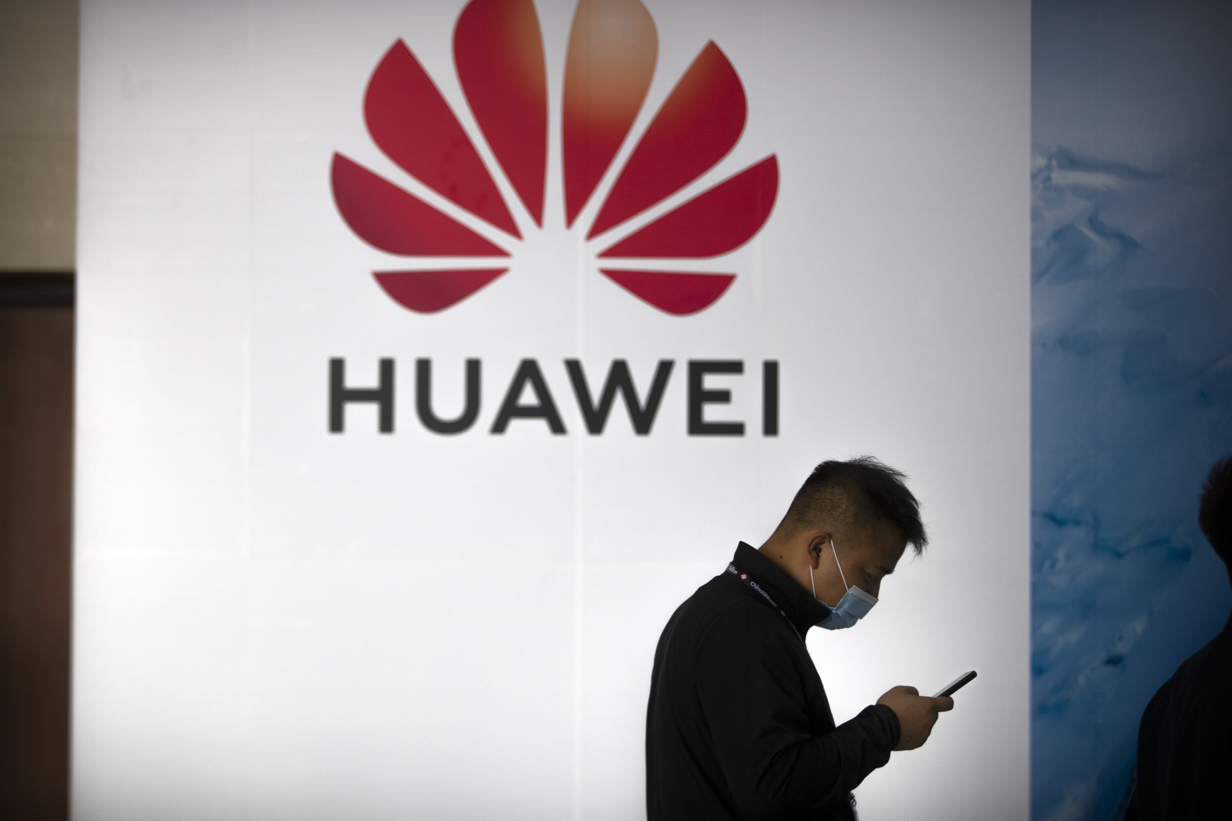 A man walks past a billboard showing the Huawei logo at the PT Expo in Beijing. Photo: AP