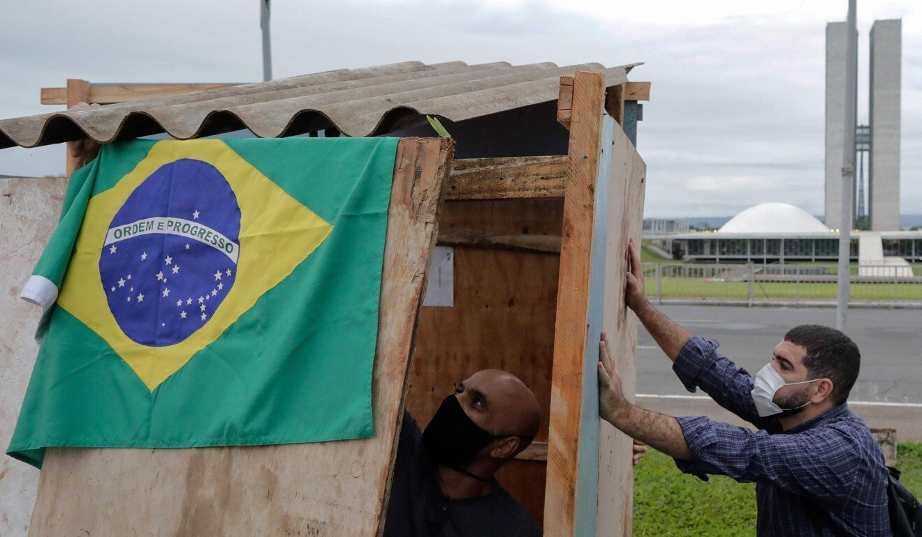 Ativistas da organização não governamental “Rio de Paz” erguem barracos simulados, que representam a vida de famílias de favelas de baixa renda no Brasil, para protestar contra a decisão do governo Bolsonaro de suspender a ajuda às pessoas mais afetadas pela pandemia.  Foto: AFP