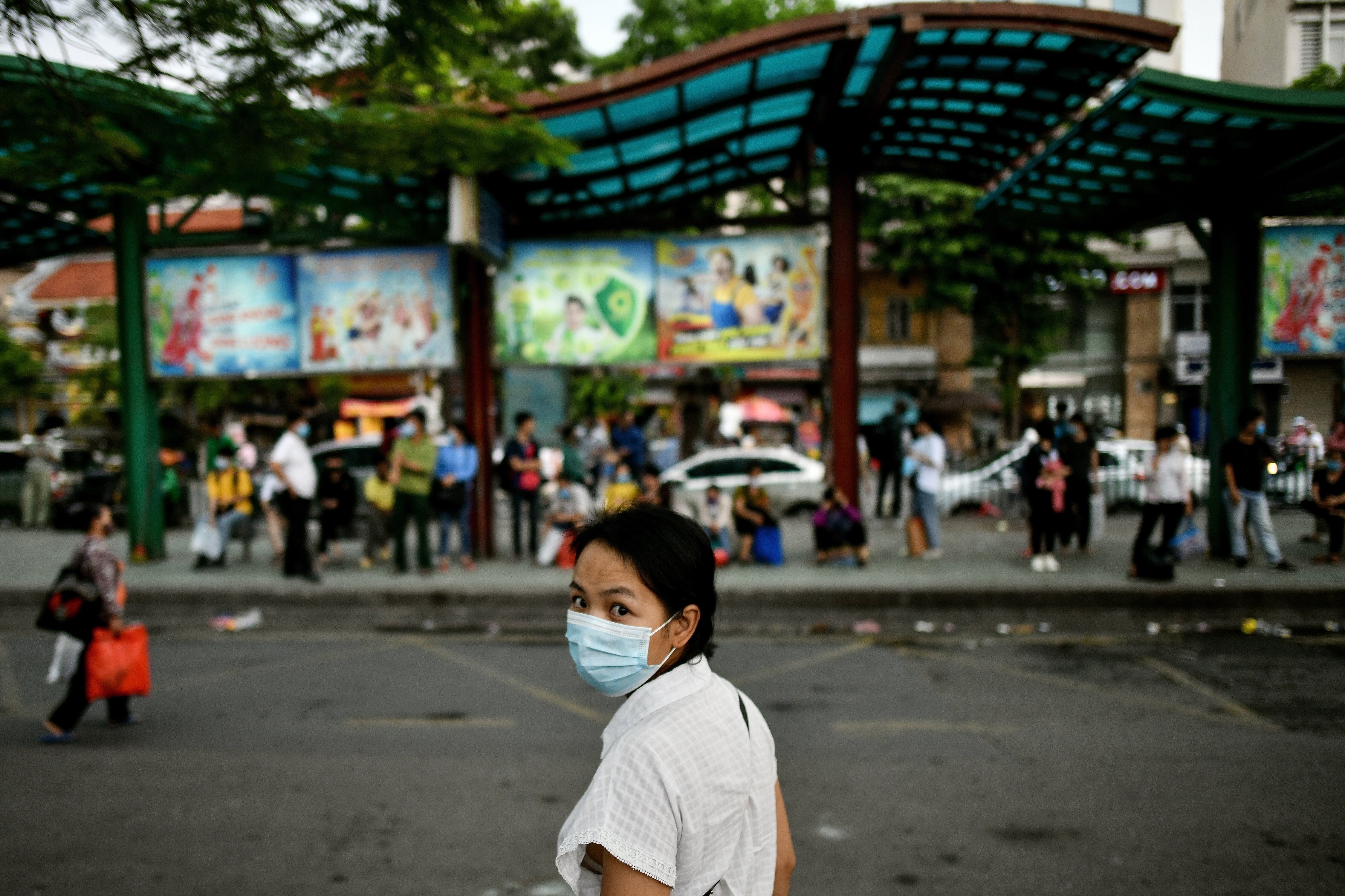 A woman wearing a face mask waits at a bus stop in Hanoi in July. Photo: AFP