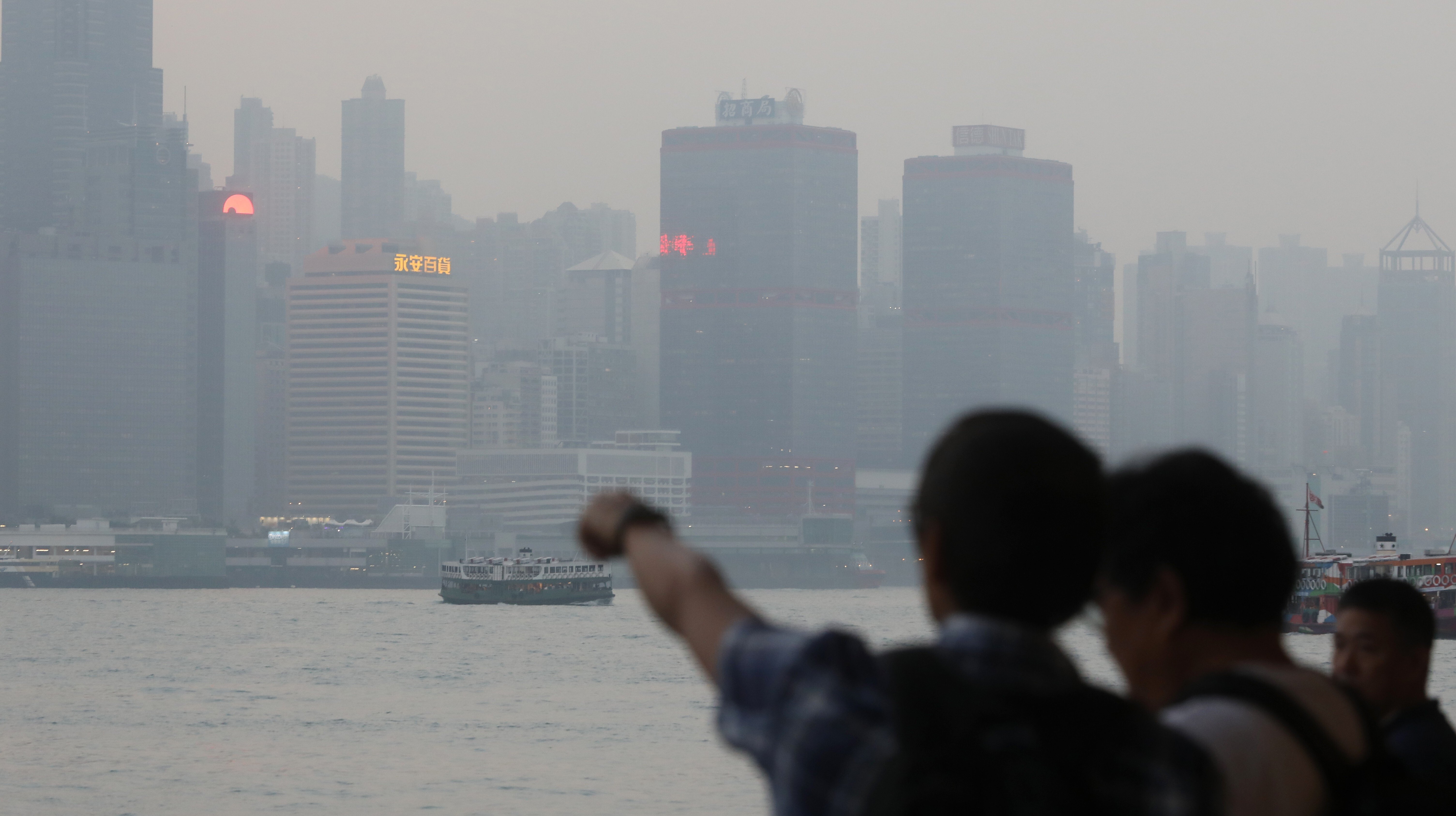 Tourists in Tsim Sha Tsui look out over Victoria Harbour on a day of poor air quality, on November 12, 2018. Photo: Sam Tsang