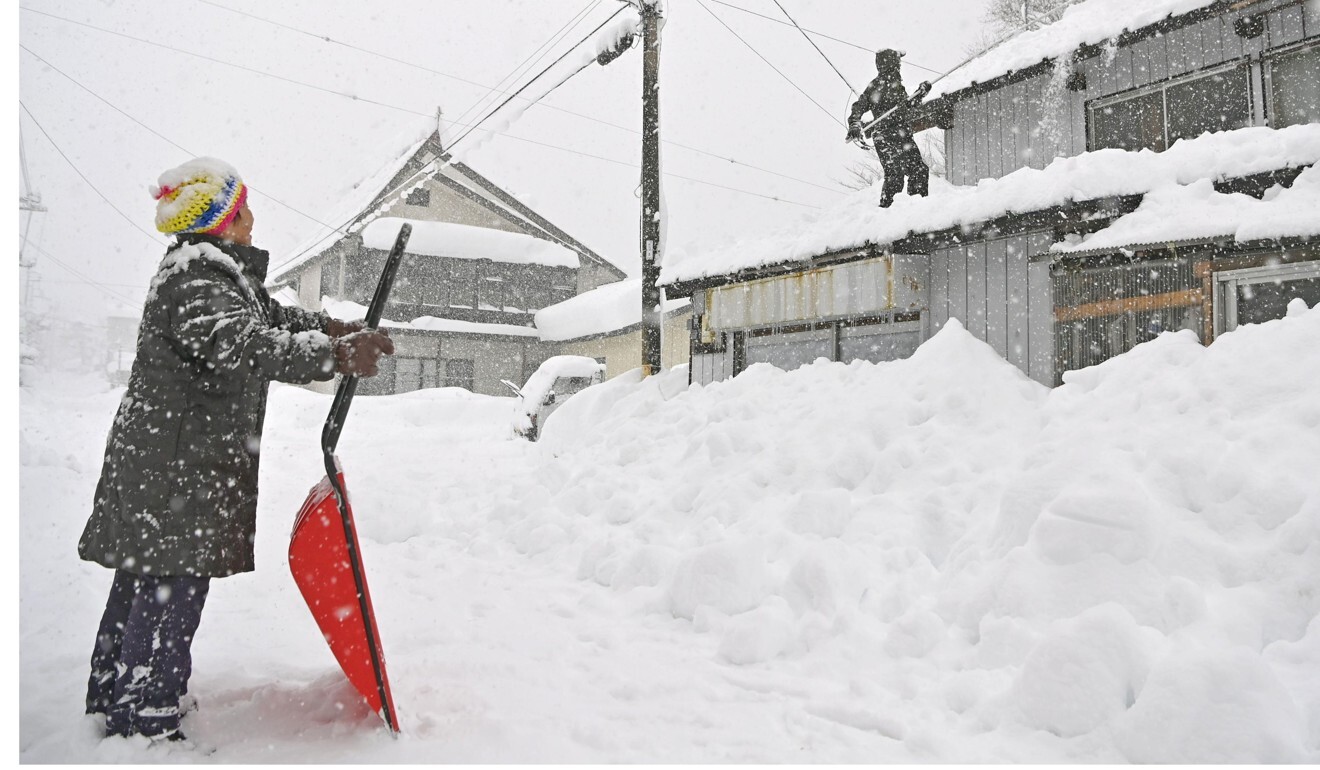 People try to remove snow from the roof of a house in Minakami, Gunma Prefecture. Photo: Kyodo