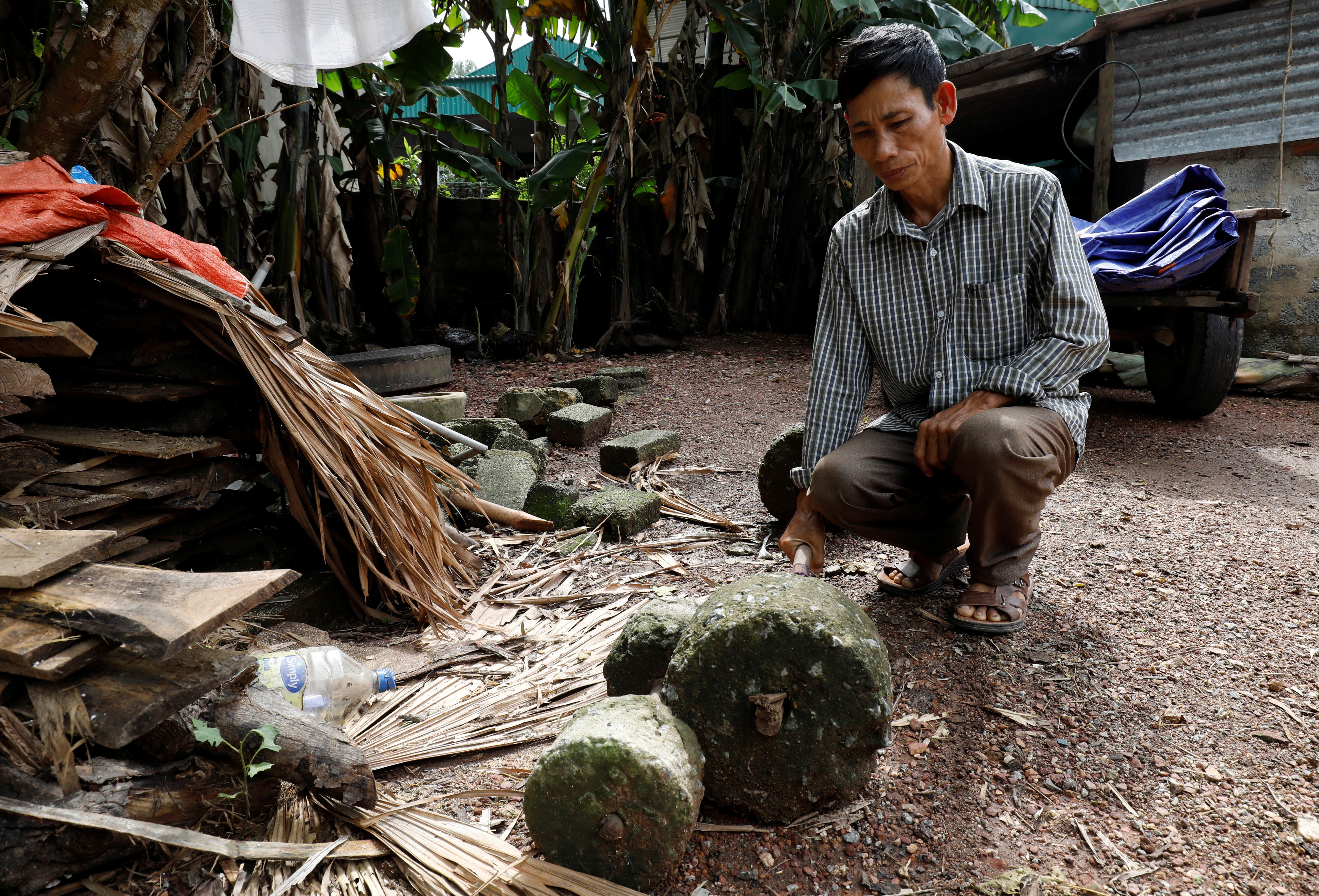 Nguyen Dinh Gia, the father of victim Nguyen Dinh Luong, kneels in his yard in Ha Tinh province, Vietnam. He said he feels sorry for the two men convicted of manslaughter as they were only trying to make a living. Photo: Reuters