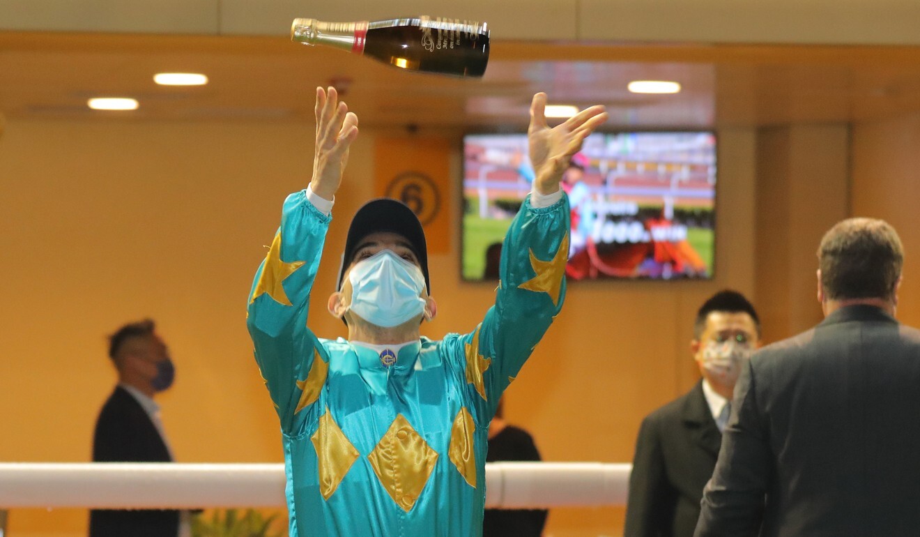 Joao Moreira throws a bottle of champagne up in the air to celebrate the milestone.