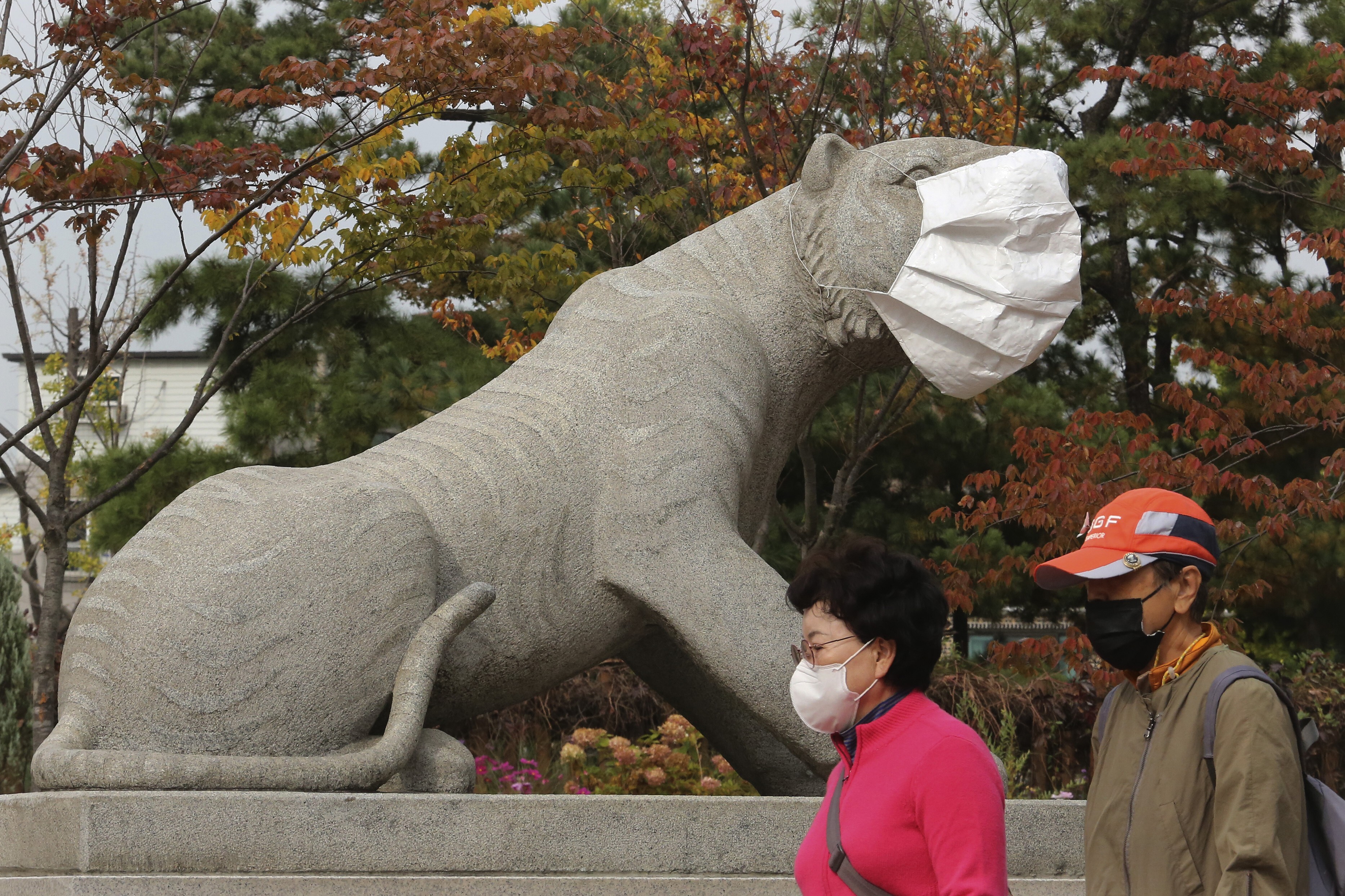 Passers-by and a statue sport face masks in a Seoul park. Photo: AP