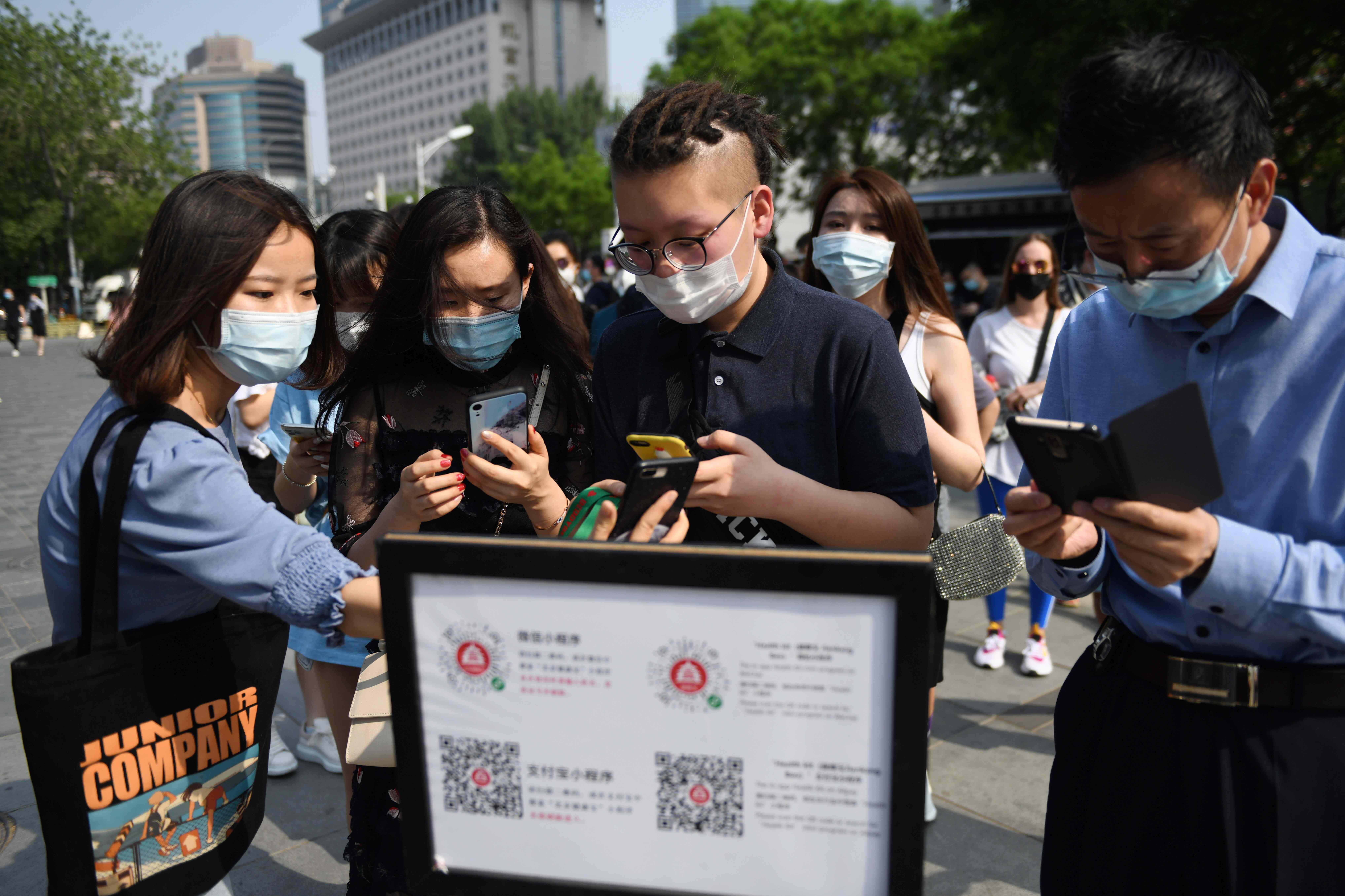 People in Beijing using a phone app to scan a code proving their health and travel status before entering a shopping mall. Photo: AFP