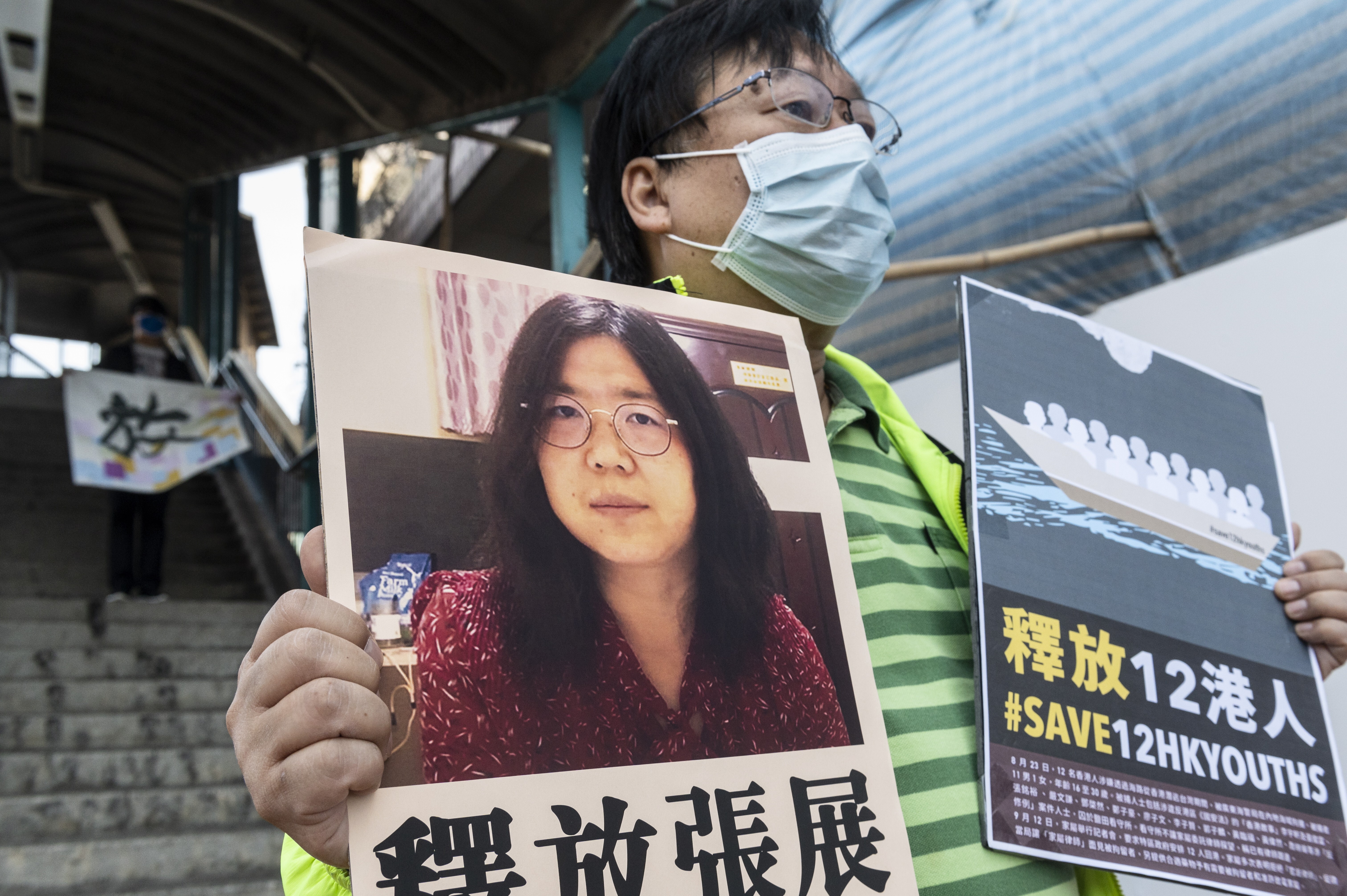 An activist near Beijing’s liaison office in Hong Kong holds up signs to support Zhang Zhan and a group of 12 Hongkongers detained on the mainland for over 130 days, on December 28. Photo: EPA-EFE