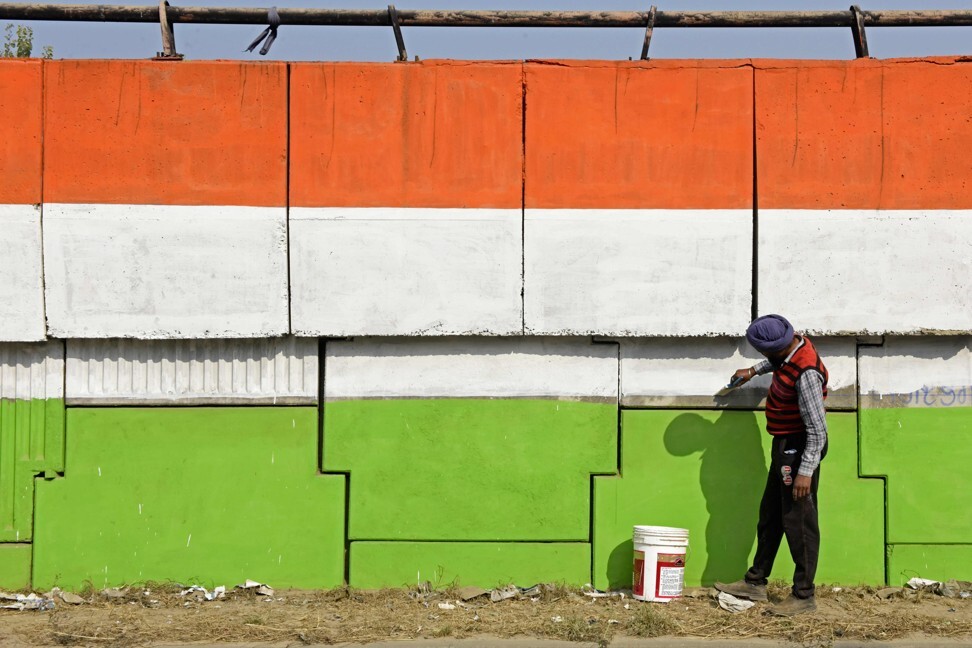 A worker paints the wall of a bridge in the colours of India's national flag, on the outskirts of Amritsar on December 23. The Indian government has consolidated 44 labour laws into four codes, which will facilitate industrialisation, generate employment and provide a social security net. Photo: AFP