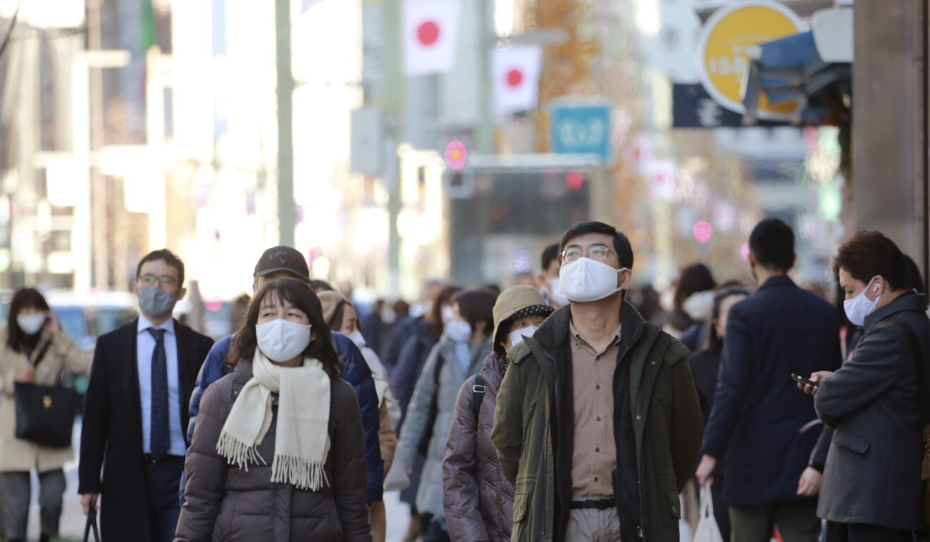 People wearing face masks to protect against the spread of the coronavirus walk along a street in Tokyo on Monday. Photo: AP
