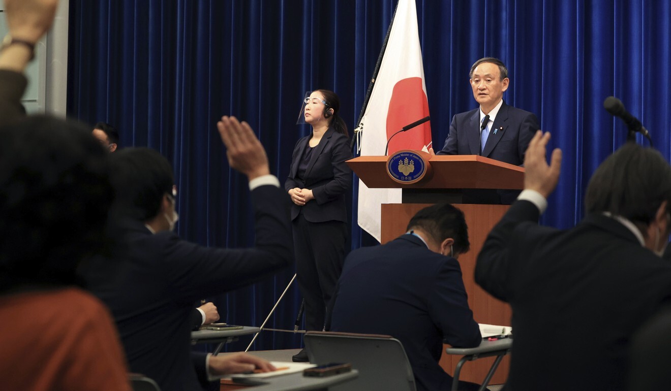 Journalists raise their hands as Japanese Prime Minister Yoshihide Suga gives a press conference at his official residence in Tokyo on Monday. Photo: AP
