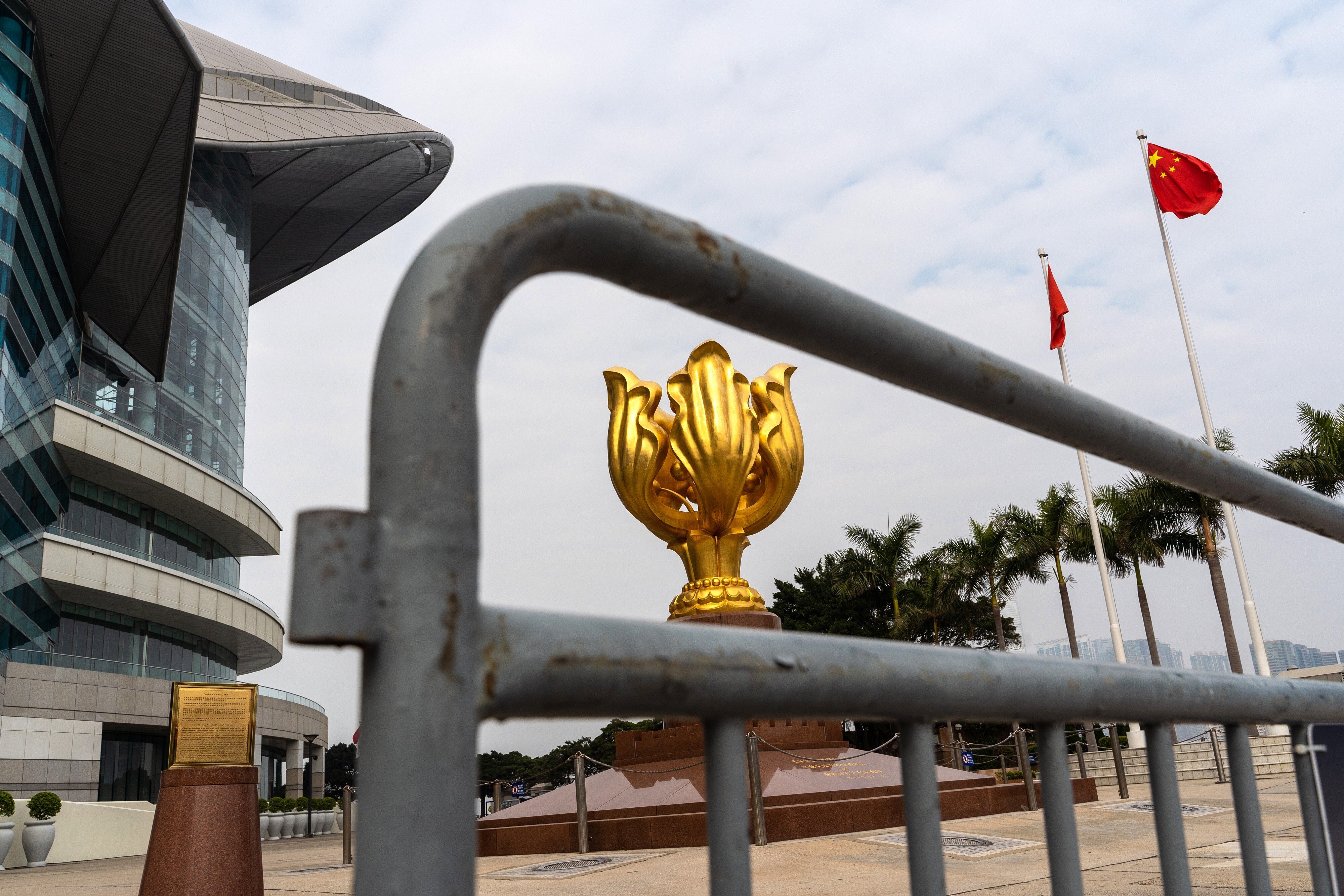 The statue of a golden Bauhinia blakeana, the symbol of Hong Kong, is seen behind a barricade while the city and national flags fly in the distance at the Golden Bauhinia Square in Wan Chai on January 7. Photo: Bloomberg