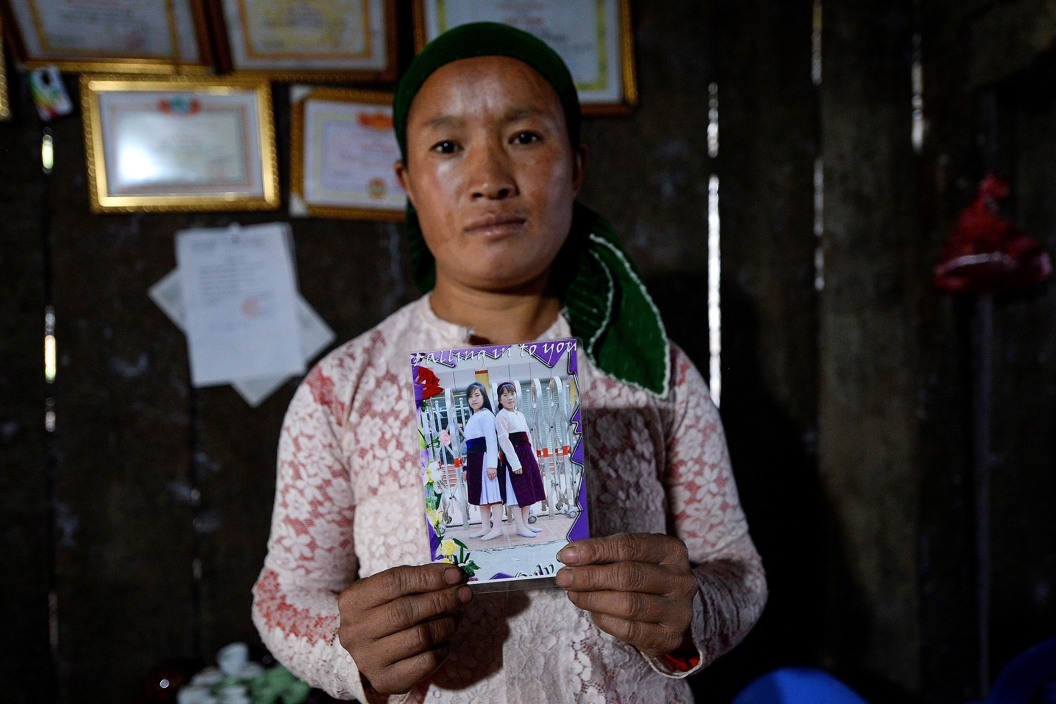 Vu Thi Dinh, a Vietnamese mother, poses with a photograph of her missing teenage daughter Dua and her best friend, at her house in Meo Vac, a mountainous border district between Vietnam’s Ha Giang province and China, on October 27, 2018. Both girls are feared to have been sold as child brides. Photo: AFP