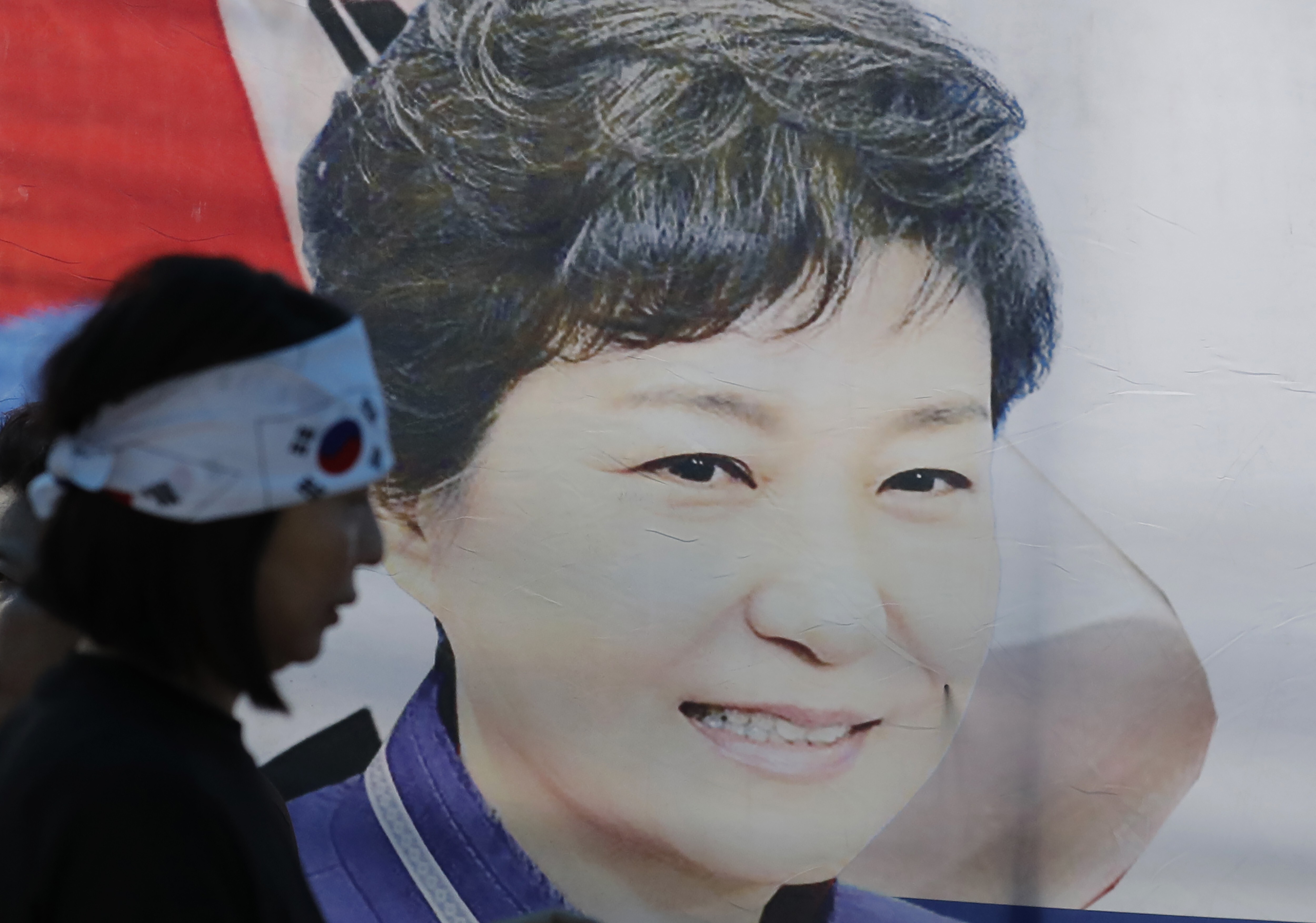 A supporter of Park Geun-hye walks past a banner with her picture in Seoul. Photo: AP