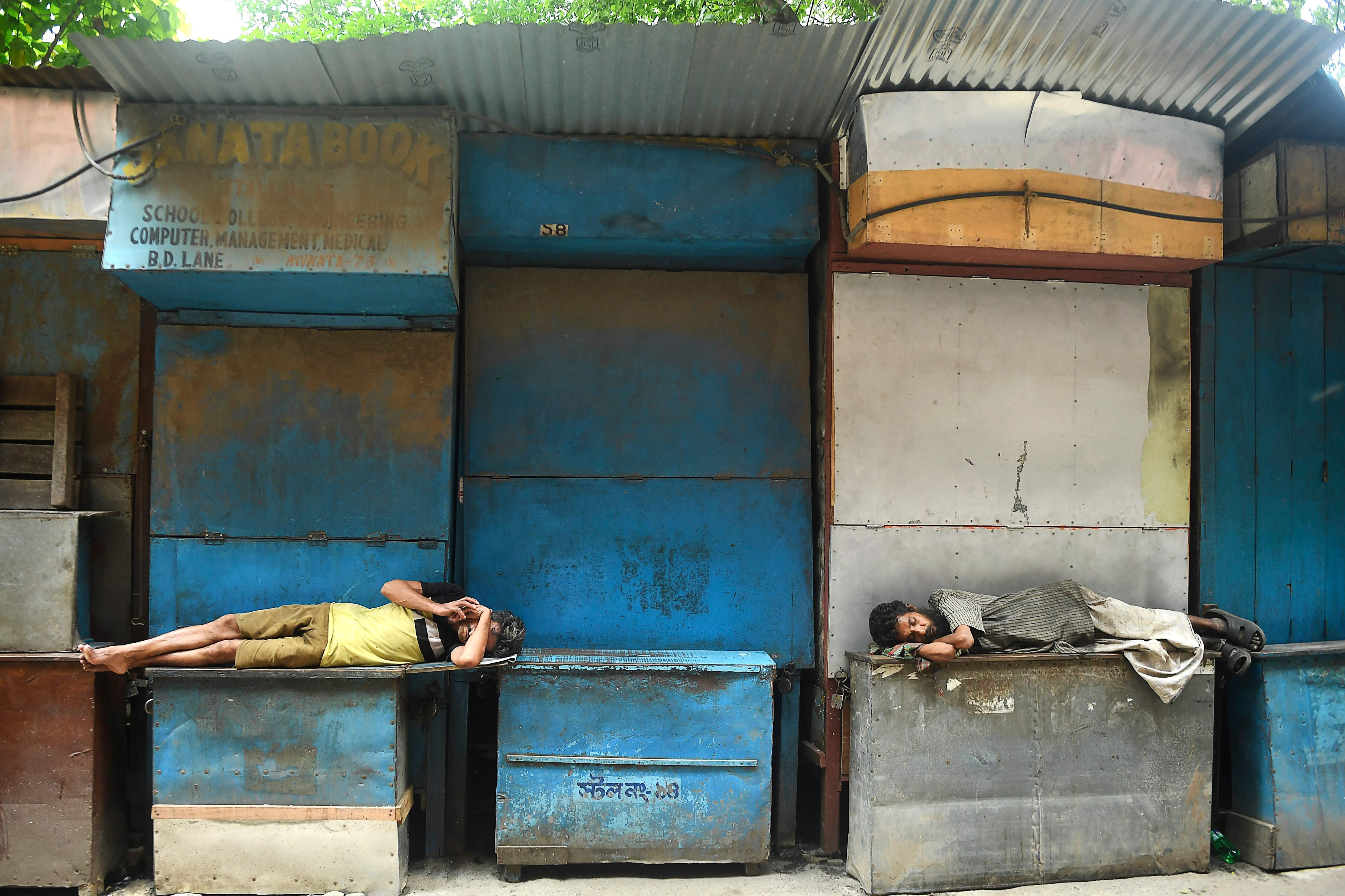 Men resting in front of closed book stalls during a coronavirus lockdown in Kolkata on August 31, 2020. Photo: AFP