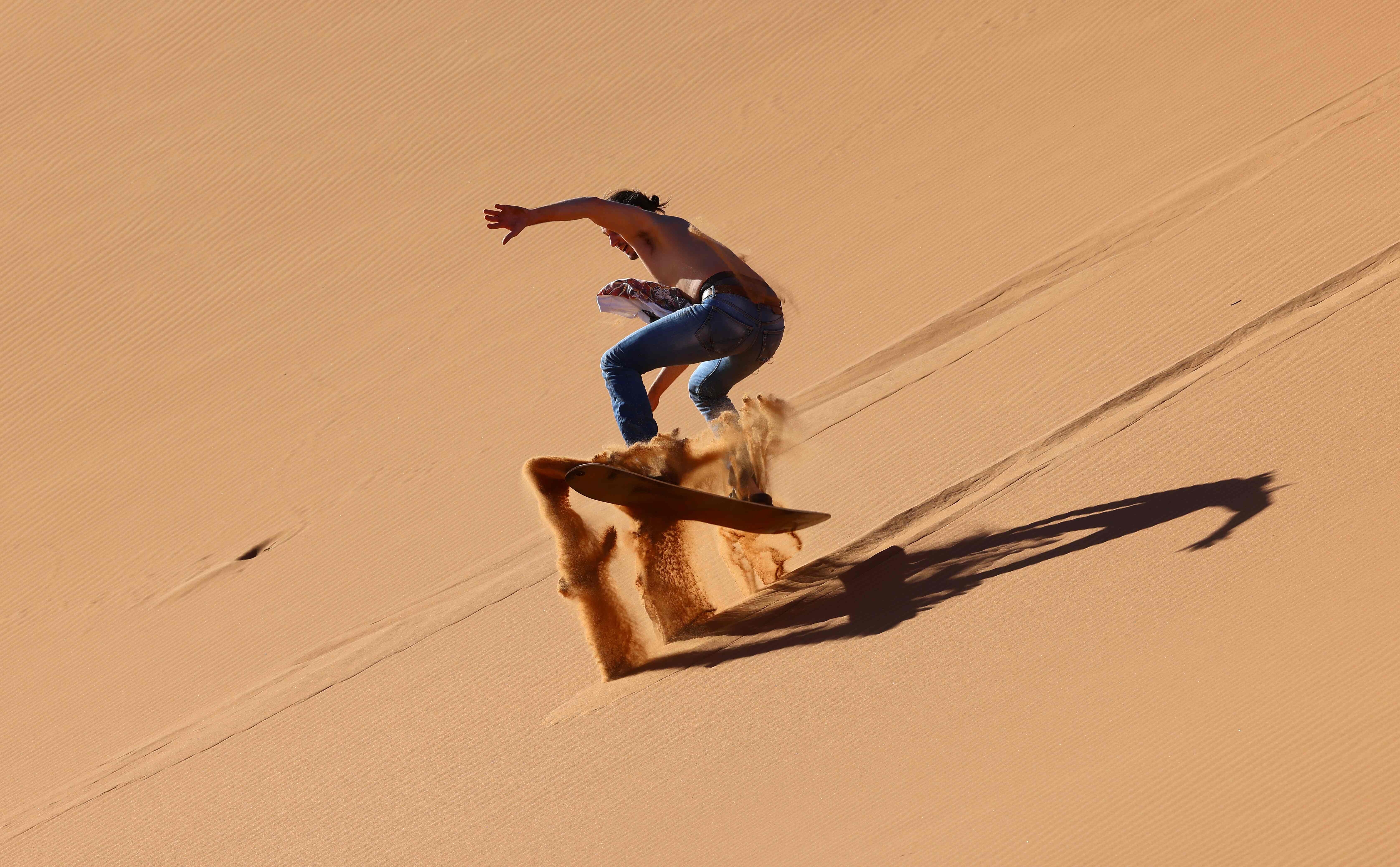 A tourist sandboarding in the Dubai desert, in the United Arab Emirates. Dubai has flung its doors open, branding itself as a sunny, quarantine-free escape from Covid-19 – despite a sharp rise in cases. Photo: AFP