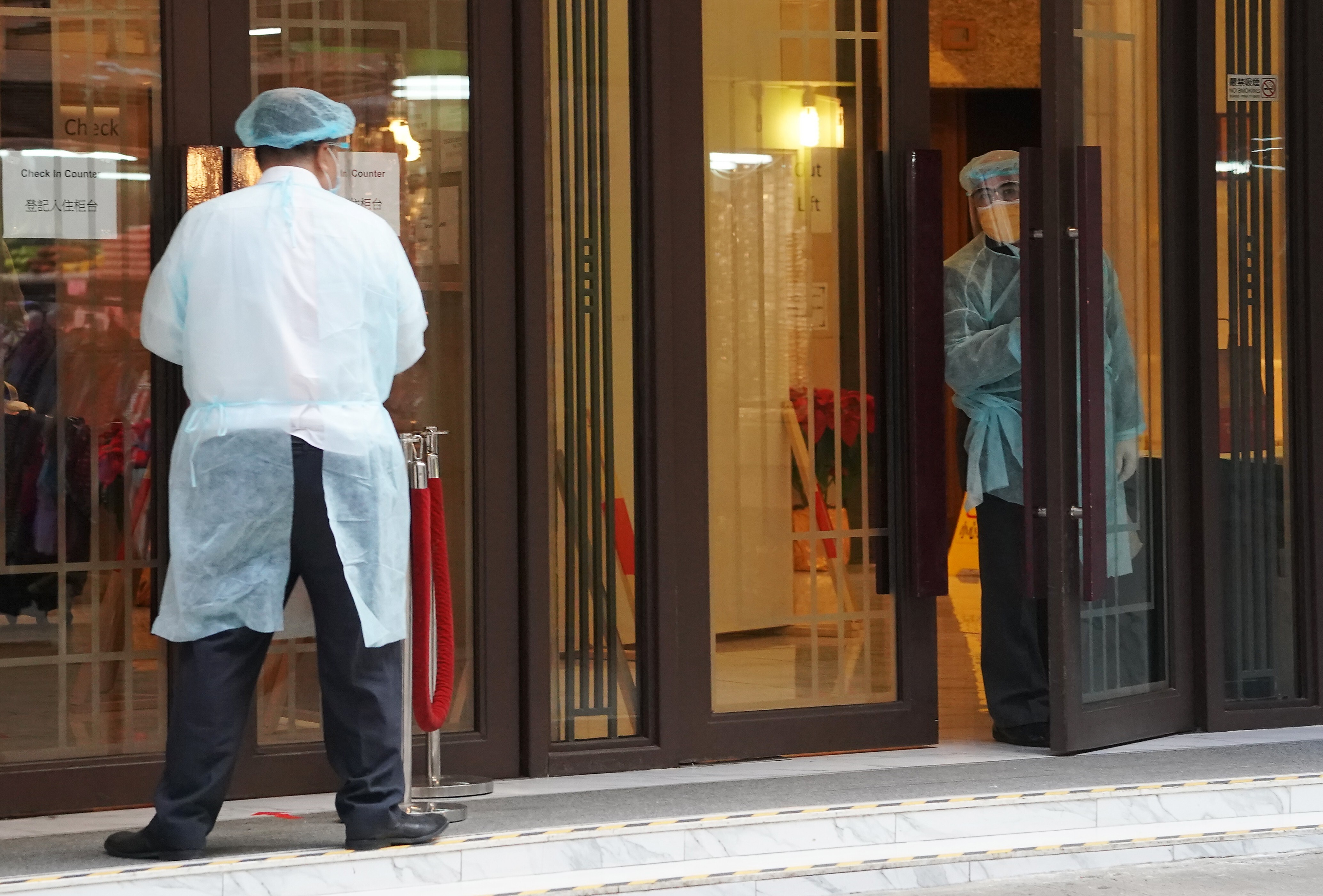 Hotel staff wearing full protective gear in North Point, Hong Kong, wait for travellers from Britain, on December 22. Photo: Felix Wong