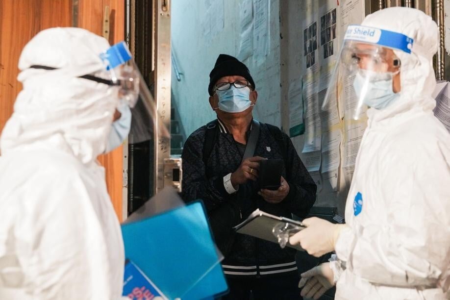 Workers in hazmat suits speak to a resident of Yau Ma Tei on Wednesday morning. Photo: SCMP/ Winson Wong