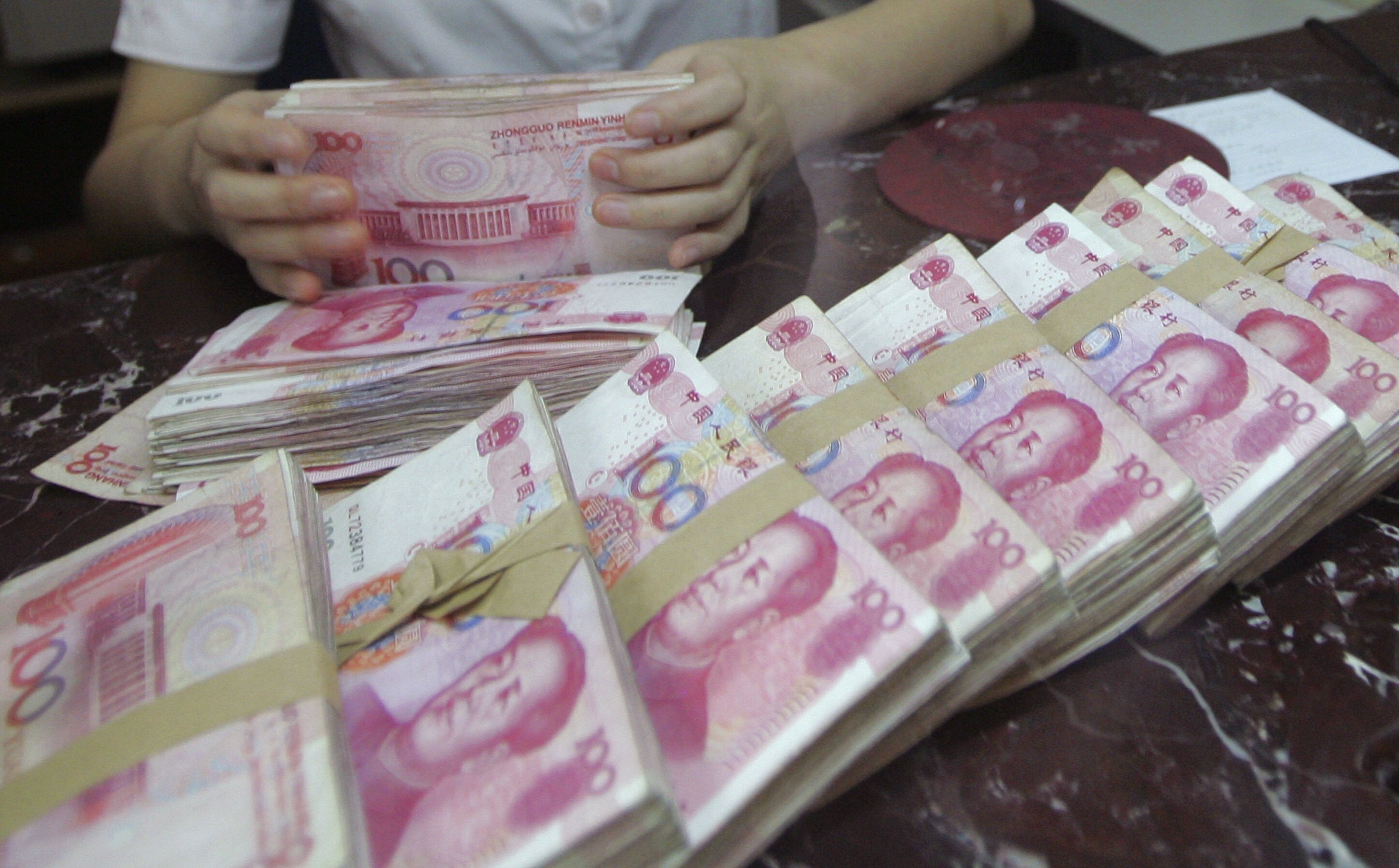 An employee counts yuan at a bank in Shenyang, Liaoning province, where the government is merging 12 small banks into one “first-class” bank. Photo: Reuters