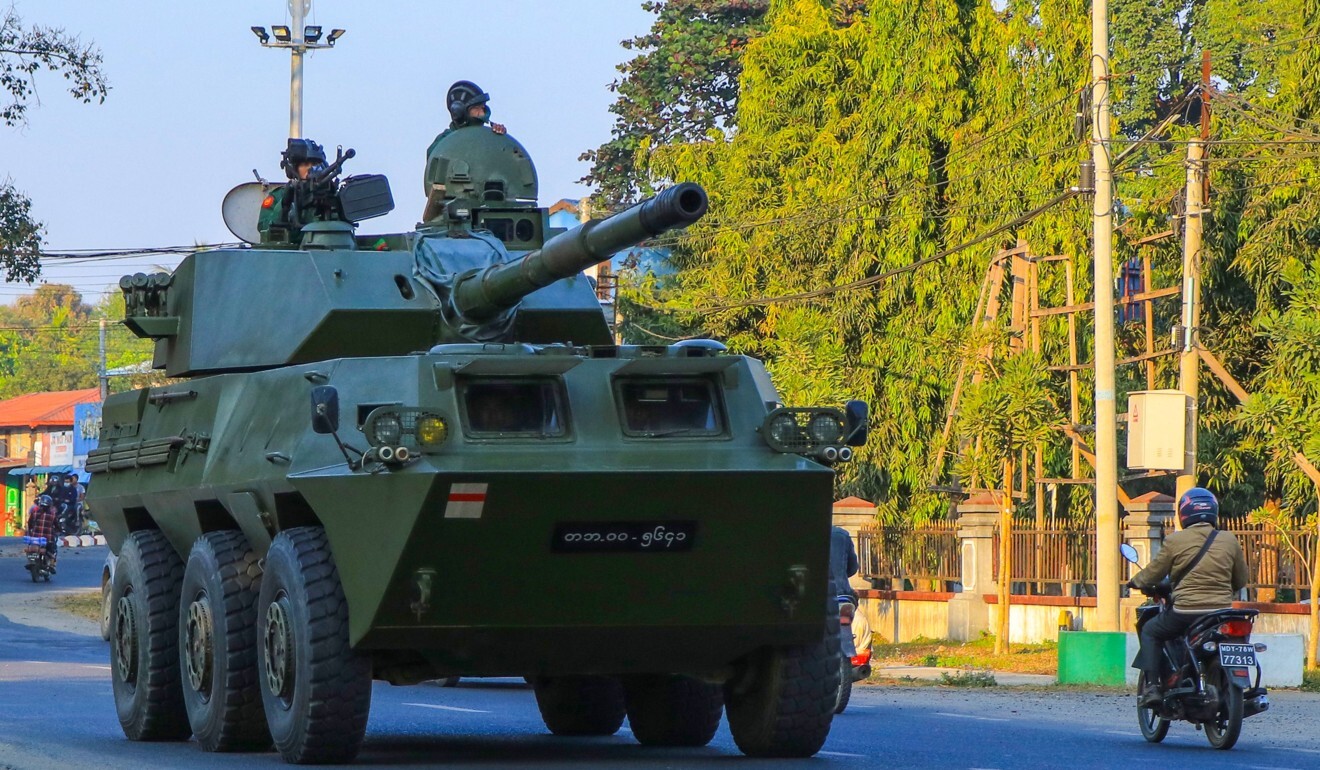 A motorcyclist rides past soldiers in an armoured vehicle in Myanmar on Wednesday. Photo: AFP